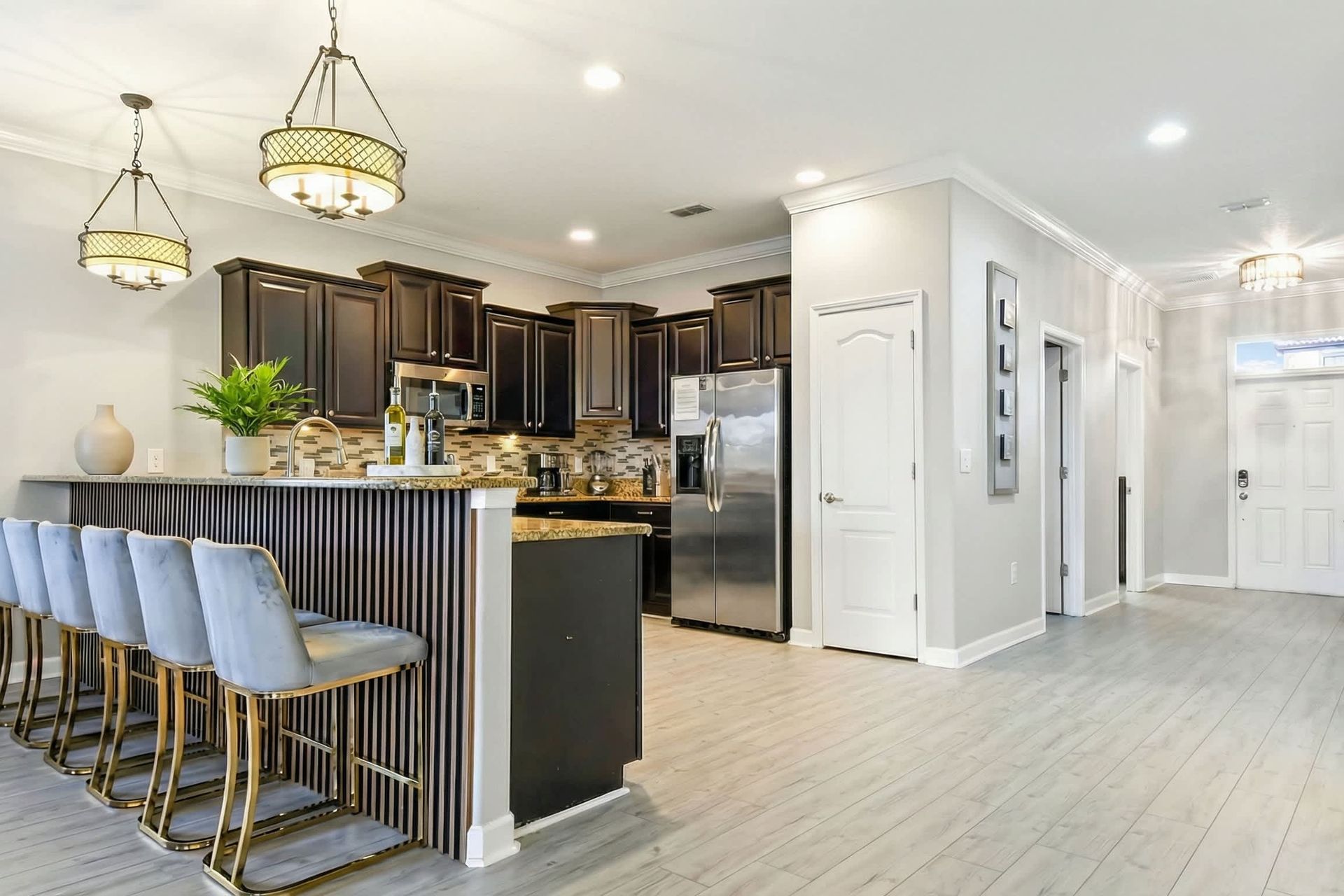Modern kitchen with a breakfast bar, elegant pendant lighting, dark wood cabinets, and stainless steel appliances.
