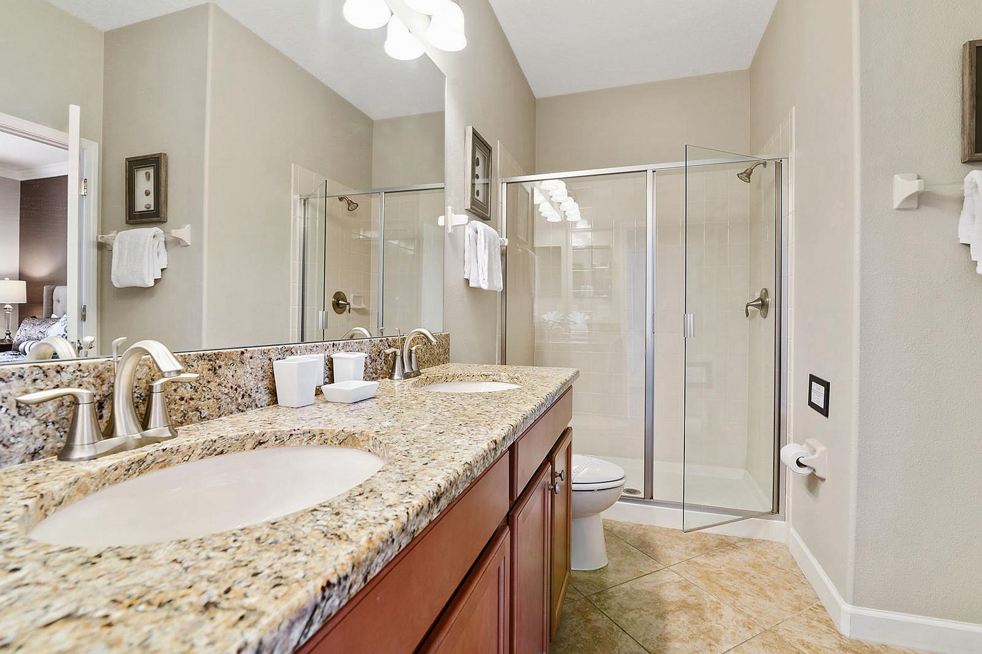 Elegant bathroom with dual sinks, granite countertops, and a spacious glass-enclosed shower.