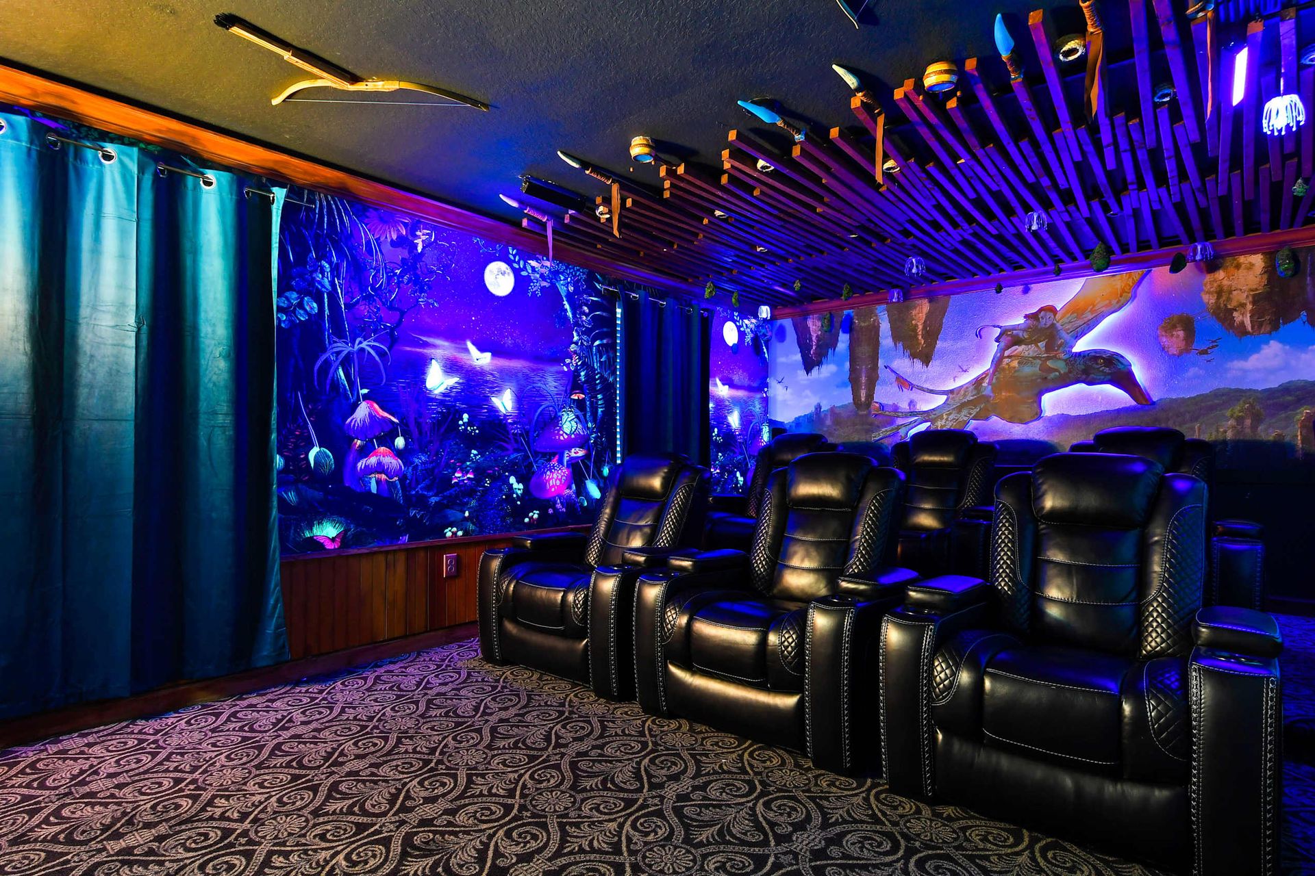 A themed home theater with black leather recliners and vibrant, glowing sci-fi murals.