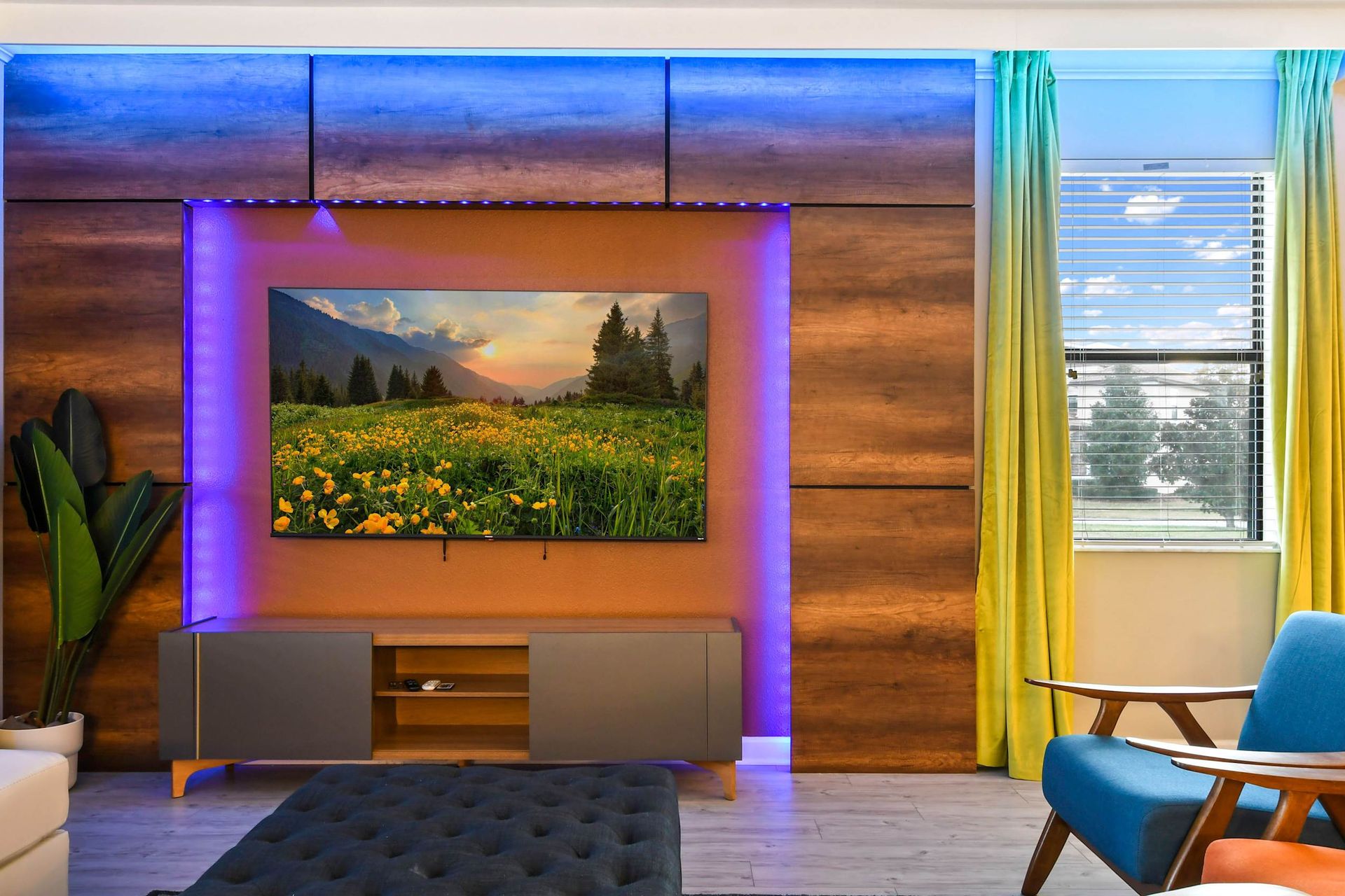 Modern living room with a vibrant LED-lit TV wall, cozy seating, and natural light.