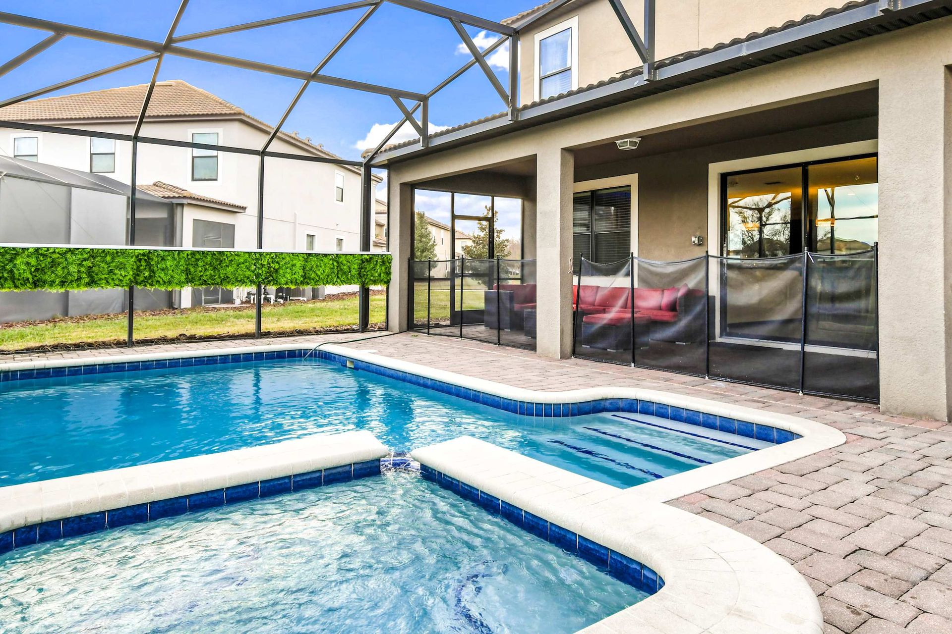 Enclosed pool area with a hot tub, lush greenery, and comfortable seating for a perfect retreat.