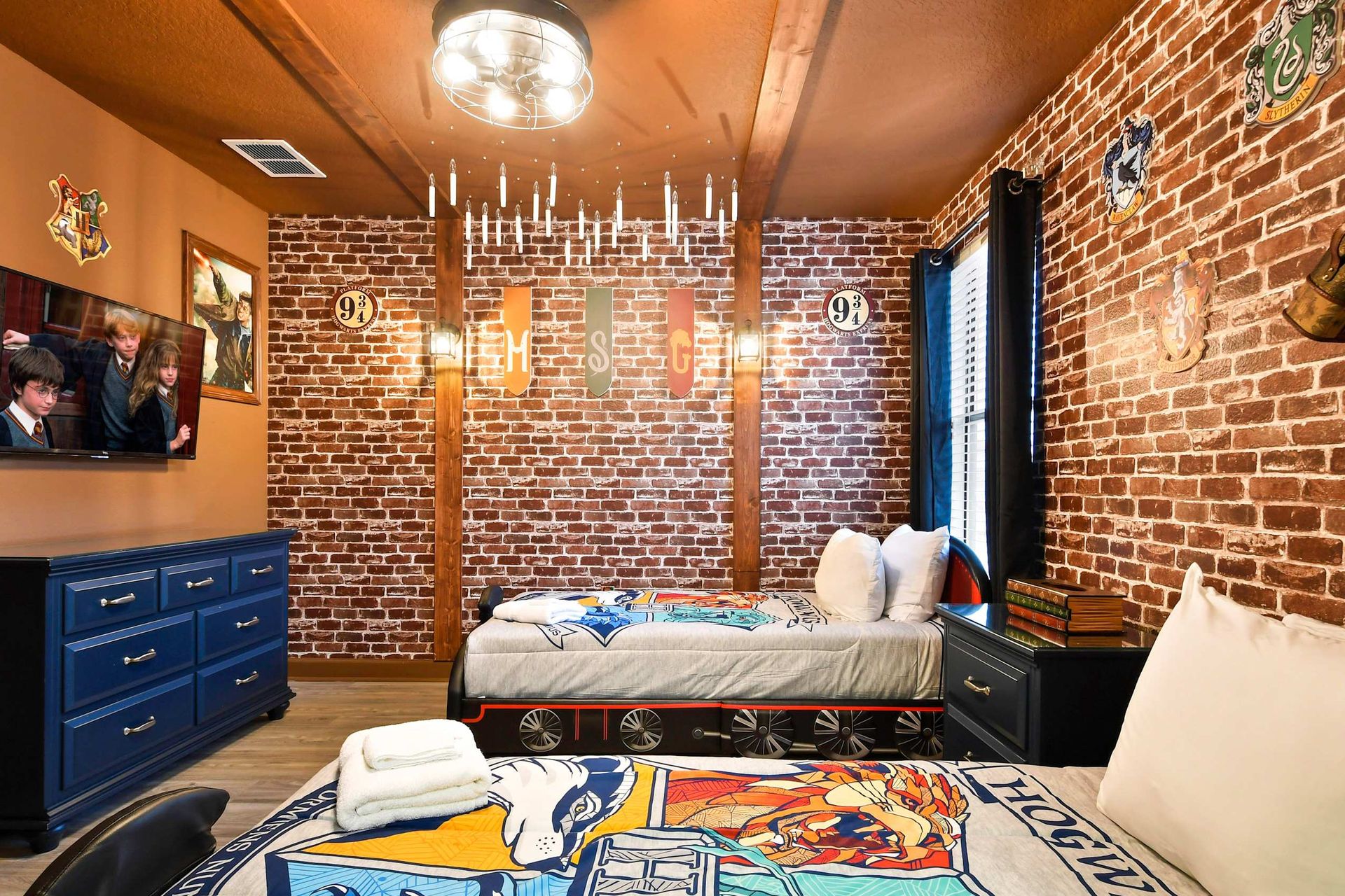 Harry Potter-themed bedroom with brick walls, floating candles, house banners, and Hogwarts Express beds.