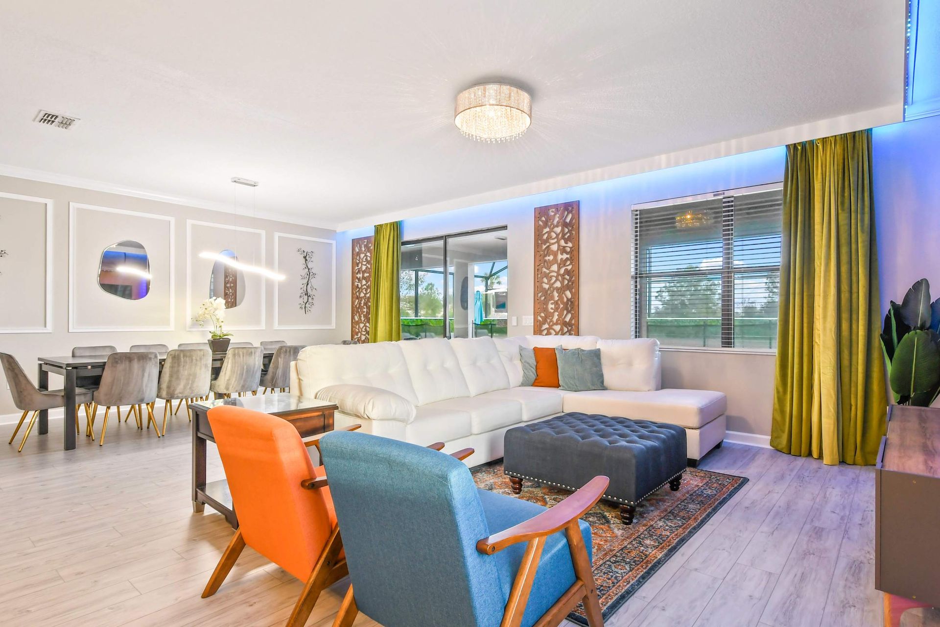 Modern open-concept living room with elegant decor, a large white sectional sofa, and a stylish dining area.