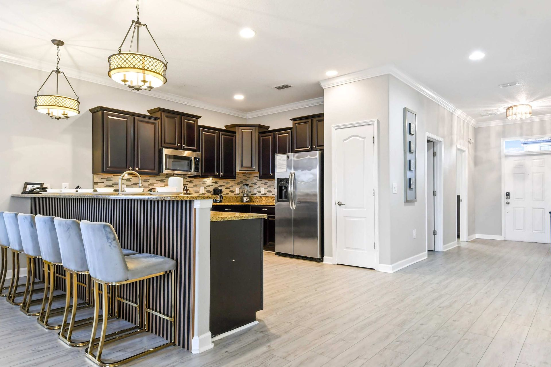 Modern kitchen with a breakfast bar, elegant pendant lighting, dark wood cabinets, and stainless steel appliances.