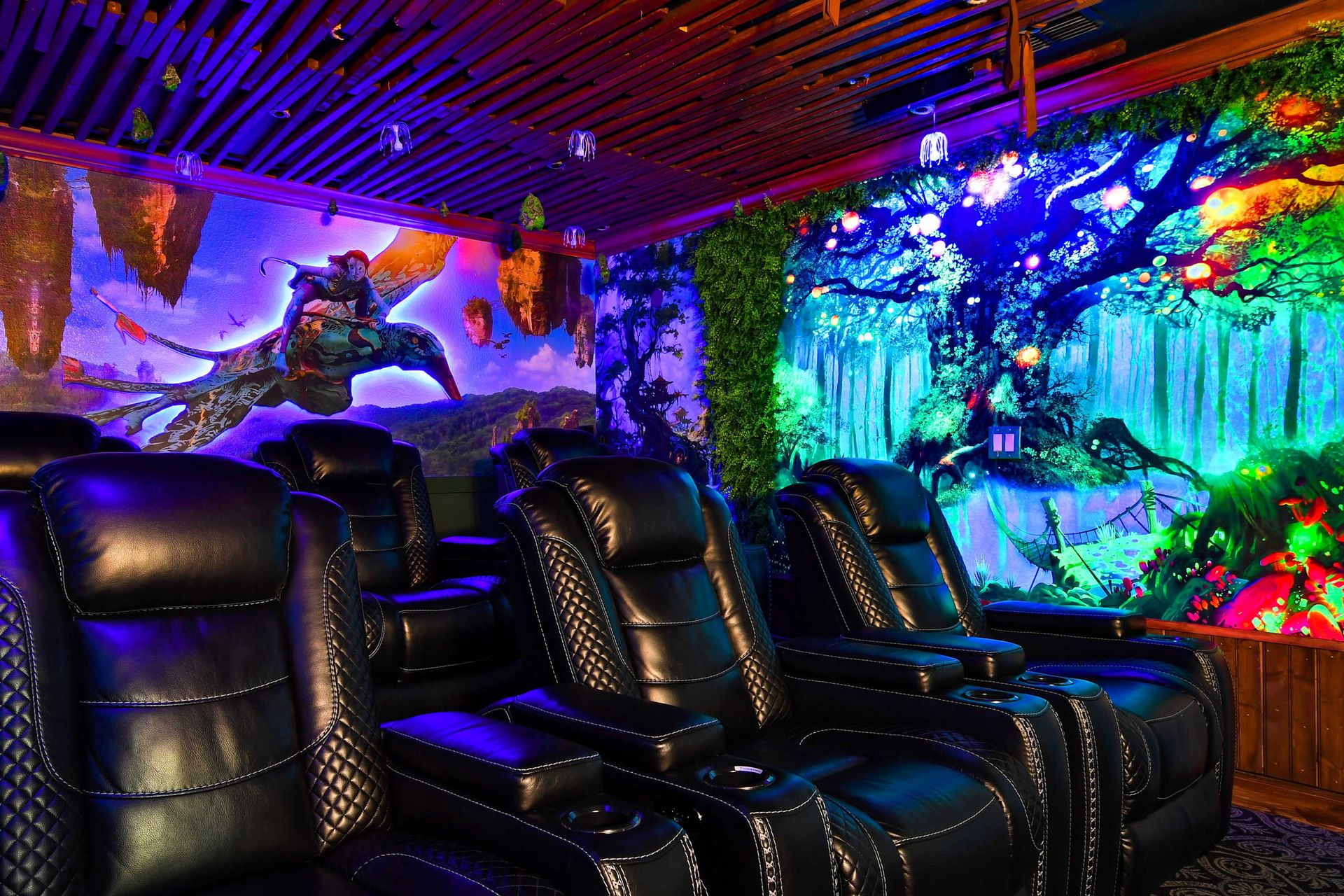 Immersive home theater with luxurious leather recliners and vibrant, fantasy-themed wall art.