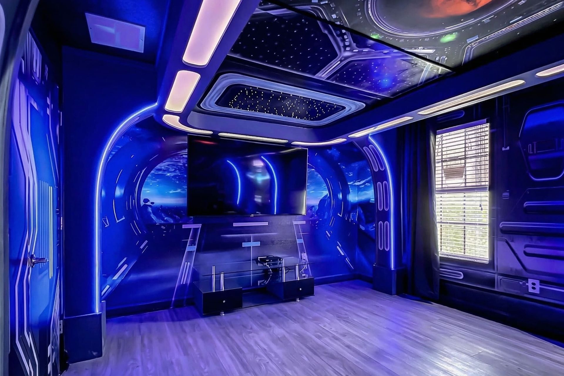 Futuristic entertainment room with a cosmic theme, ambient lighting, and a large screen for immersive viewing.