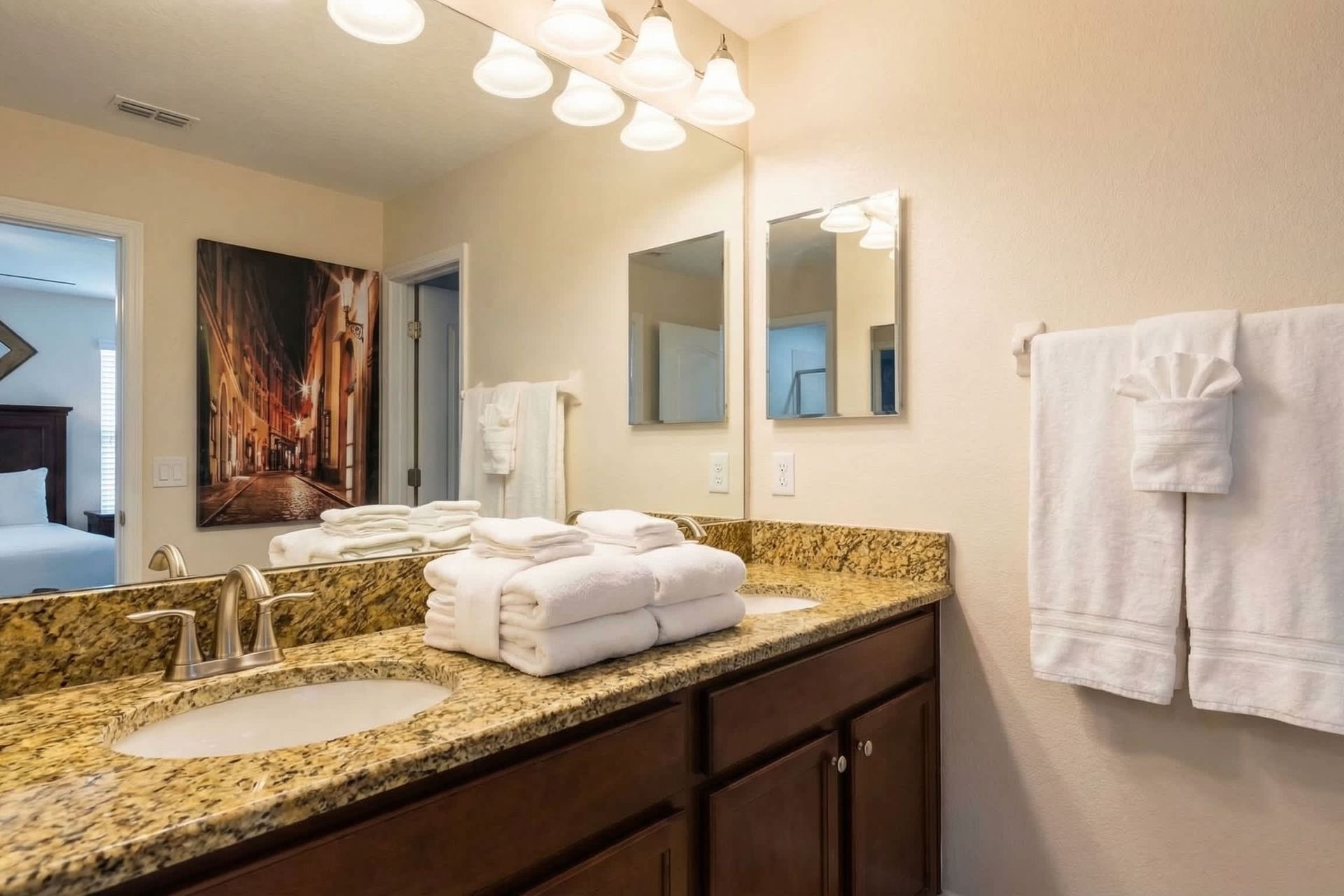 Spacious bathroom with dual granite sinks, ample lighting, and an entry to a modern bedroom with chic decor.
