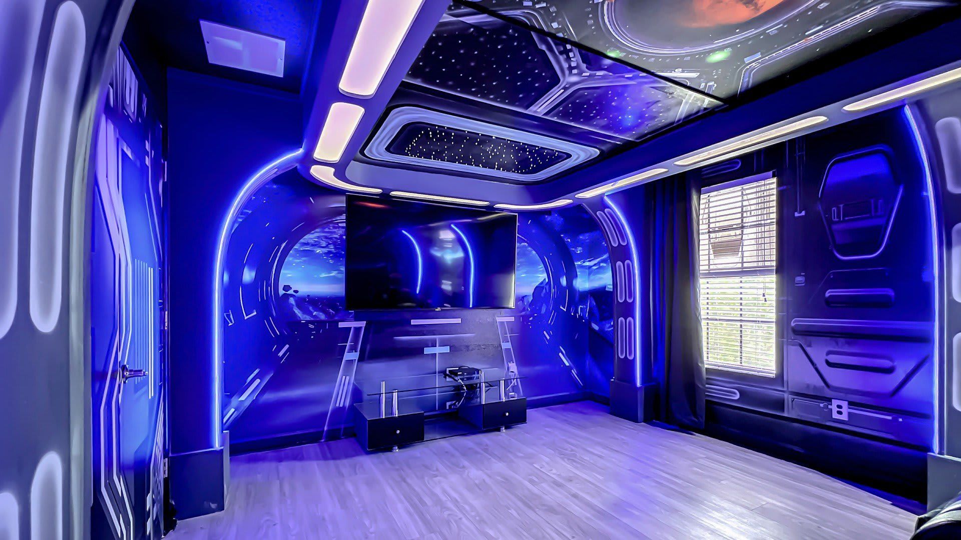 Futuristic entertainment room with a cosmic theme, ambient lighting, and a large screen for immersive viewing.