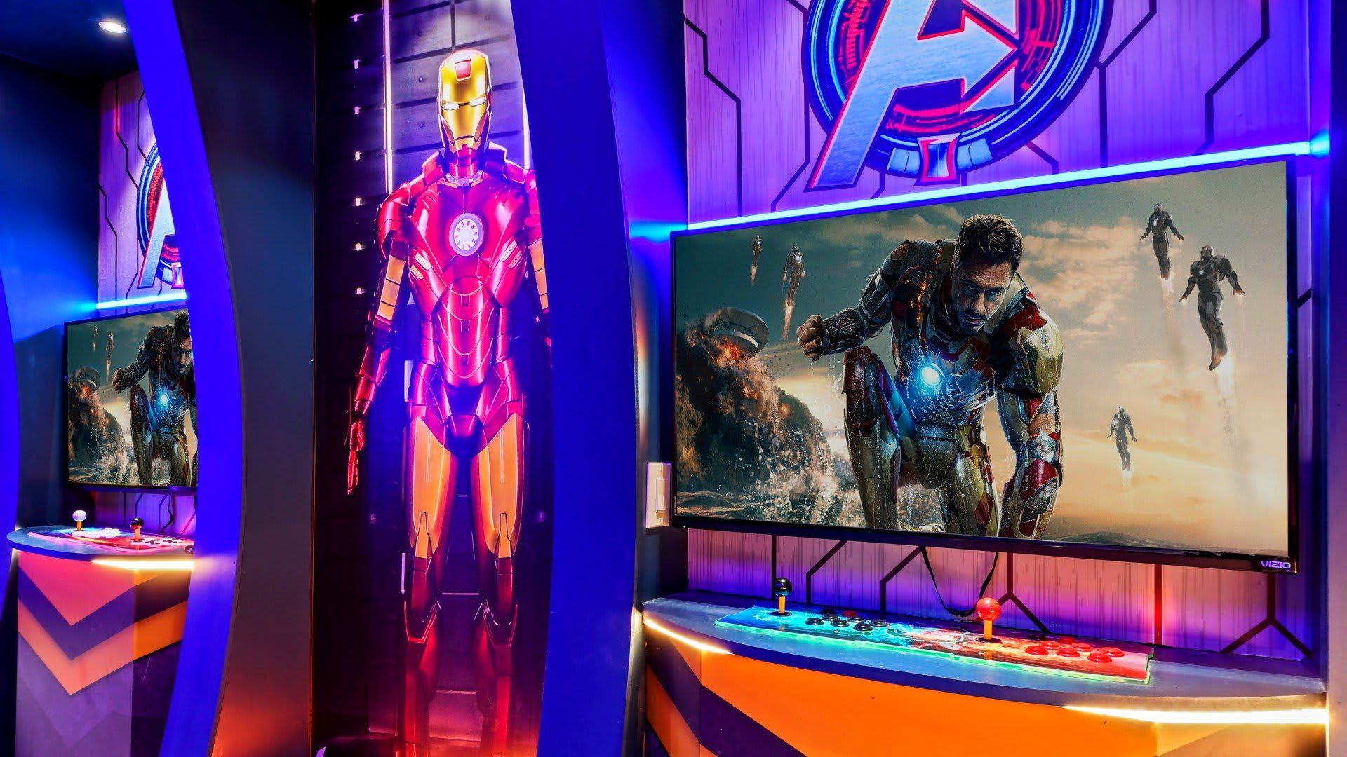 Avengers-themed gaming room with arcade setup, large screens, vibrant lighting, and Iron Man decor.