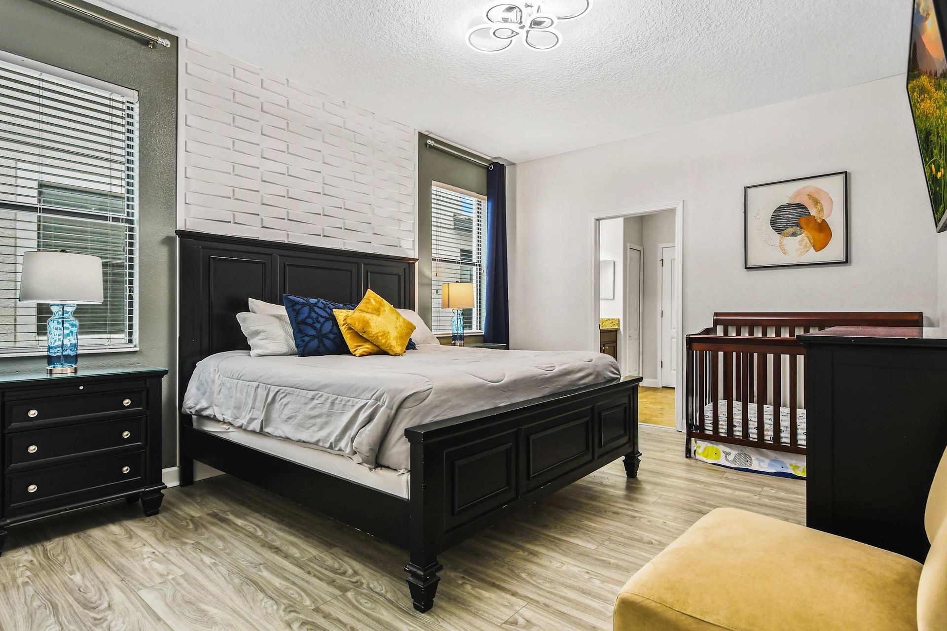 Opulent master bedroom boasts a spacious king bed, complemented by a crib for added comfort