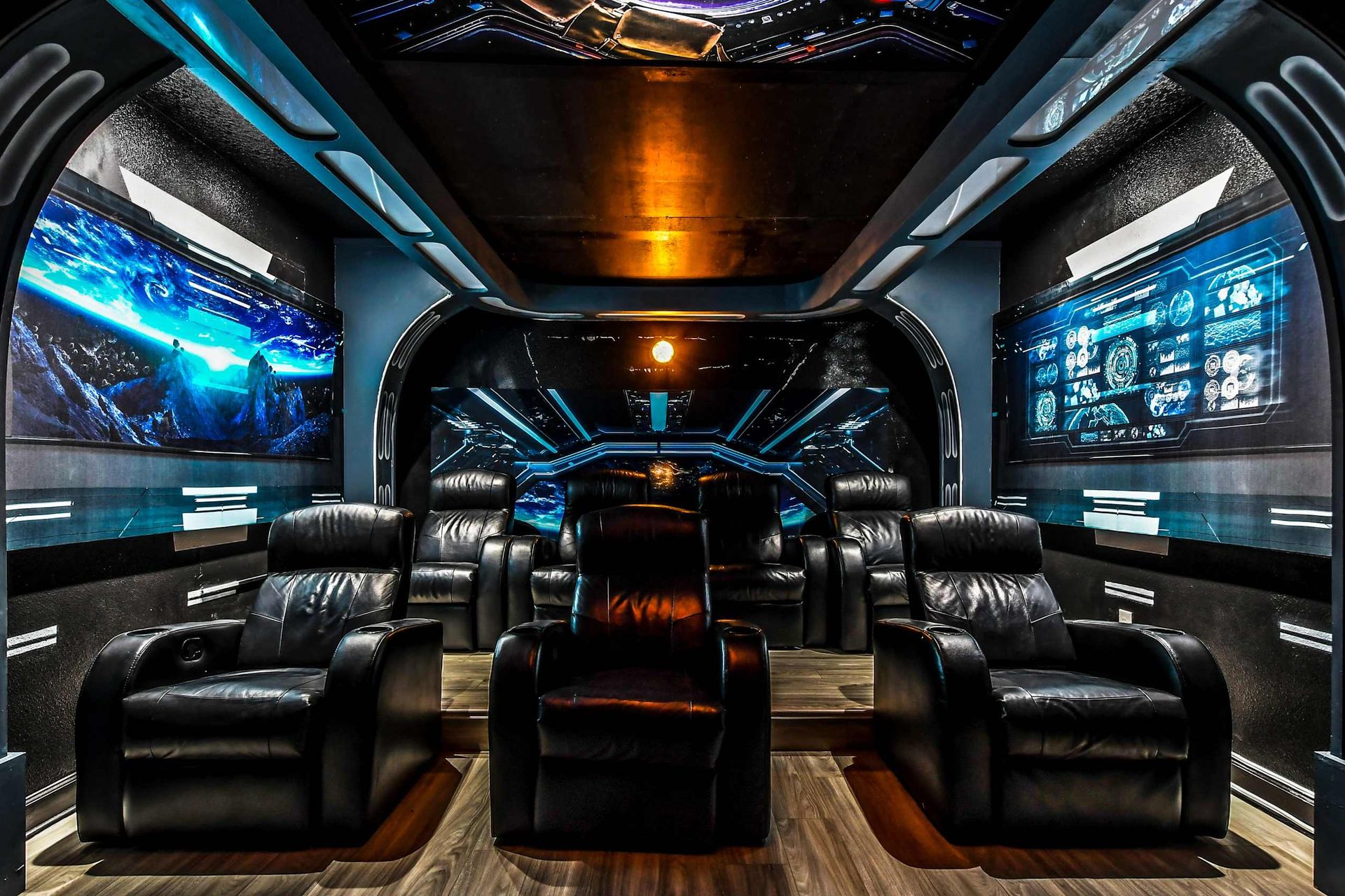 Sci-fi-themed home theater with comfortable black leather recliners, futuristic decor, and cosmic visuals.