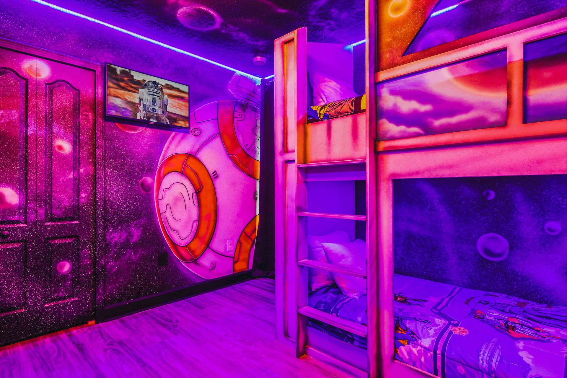 Star Wars-themed kids' bedroom with neon lighting, cosmic wall murals, custom bunk beds, and a TV.