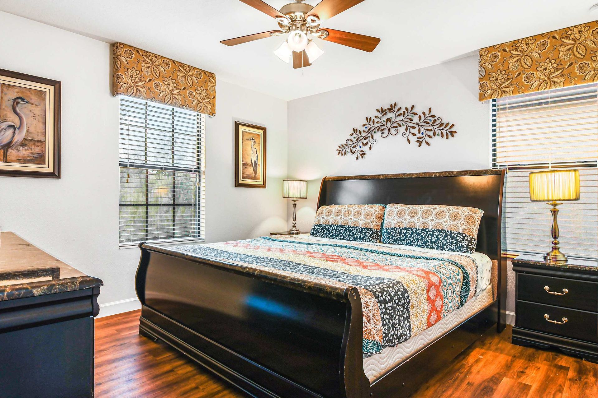 A warm bedroom with a patchwork quilt, dark wood sleigh bed, and nature-themed wall decor.