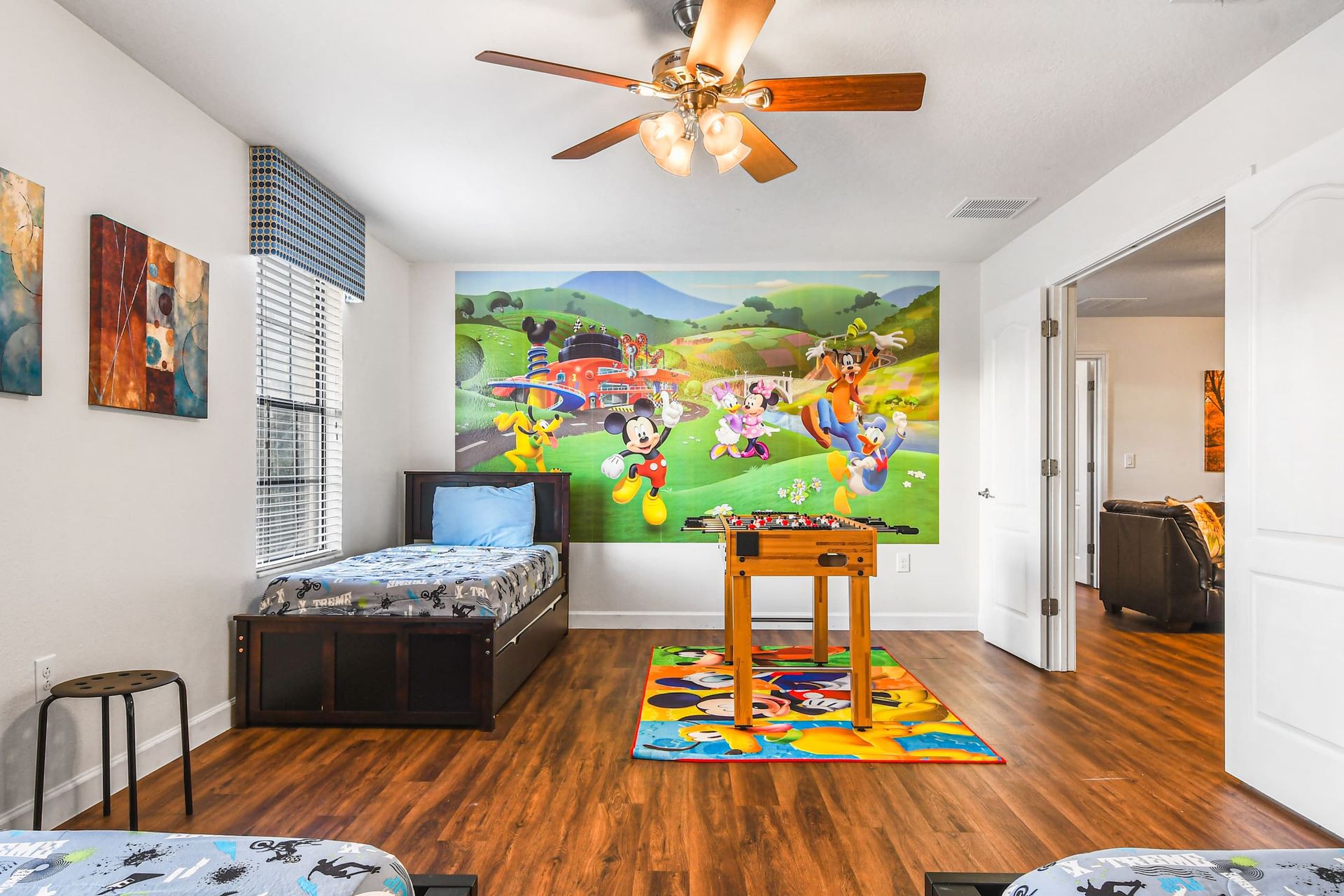 A playful kids' room with character-themed decor, twin beds, and a foosball table for entertainment.
