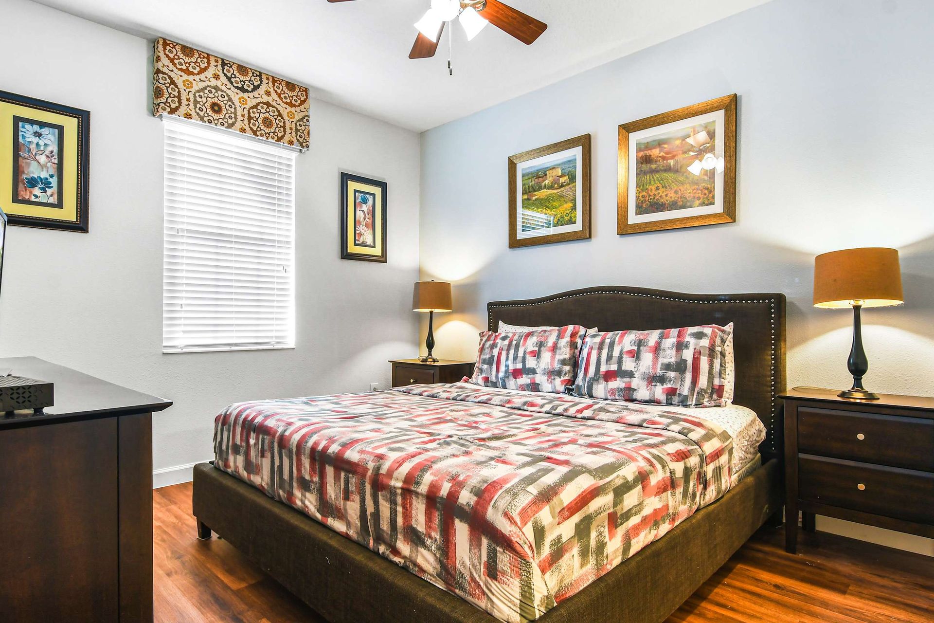 A stylish bedroom featuring a modern plaid bedspread, dark wood furniture, and elegant framed art.
