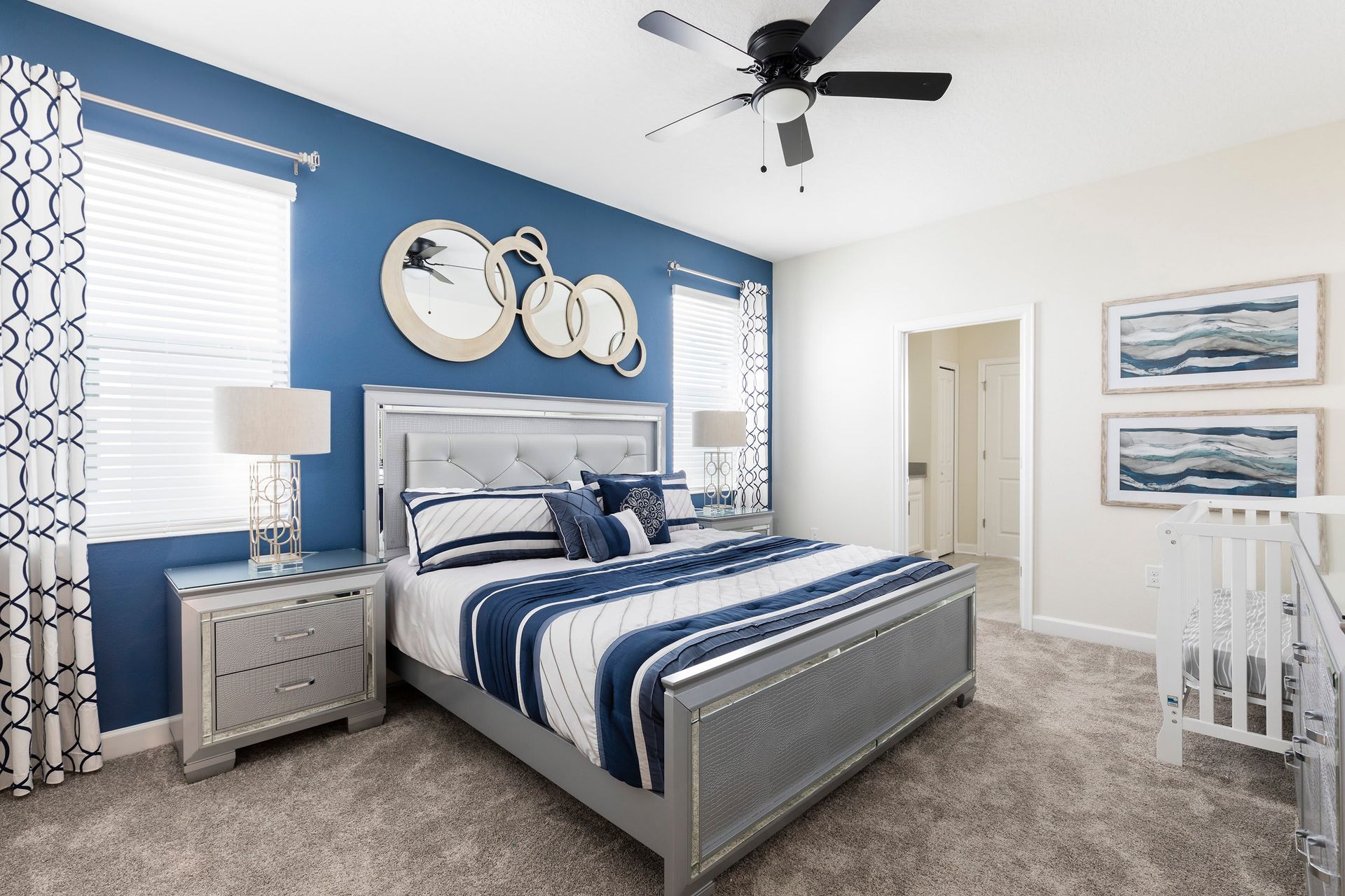 Elegant master suite with king bed, chic decor, and cozy crib setup
