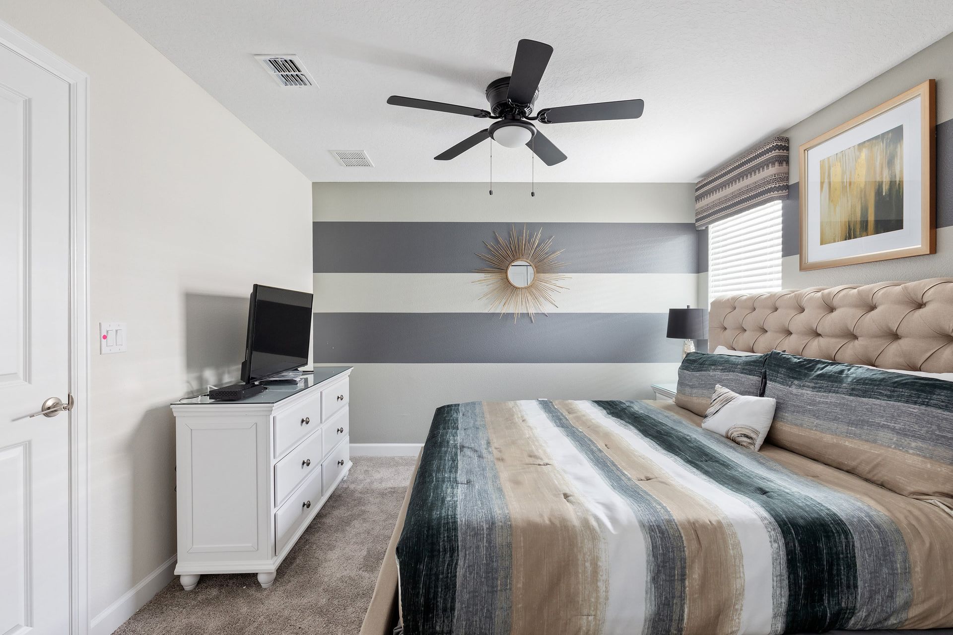 Stylish bedroom with king bed, striped accent wall, and cozy vibes!