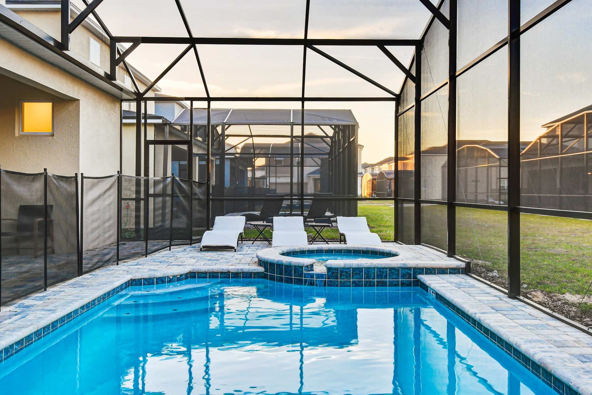 Relaxing private pool and spa with loungers in a screened, sunlit enclosure.
