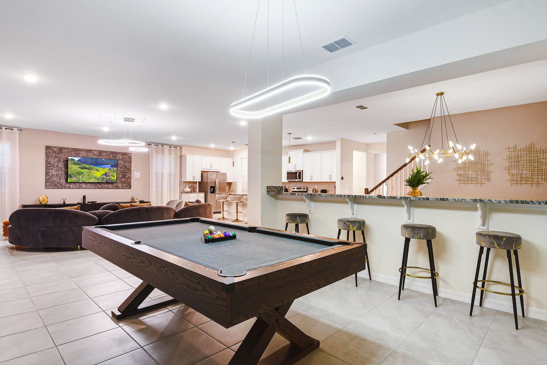 Open-concept living area with a pool table, modern kitchen, and cozy seating.