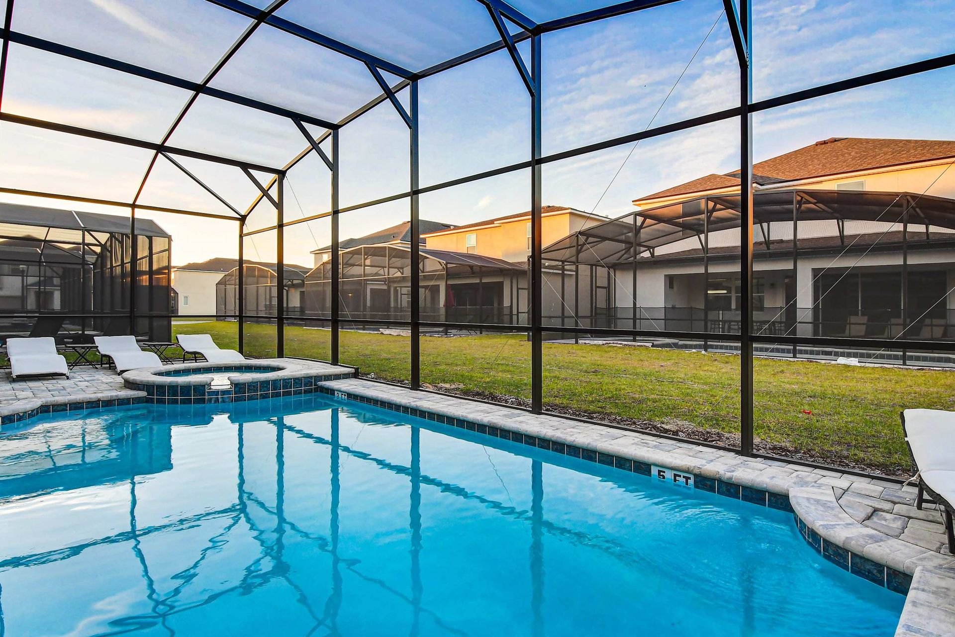 Private screened-in pool with spa, sun loungers, and serene outdoor views.