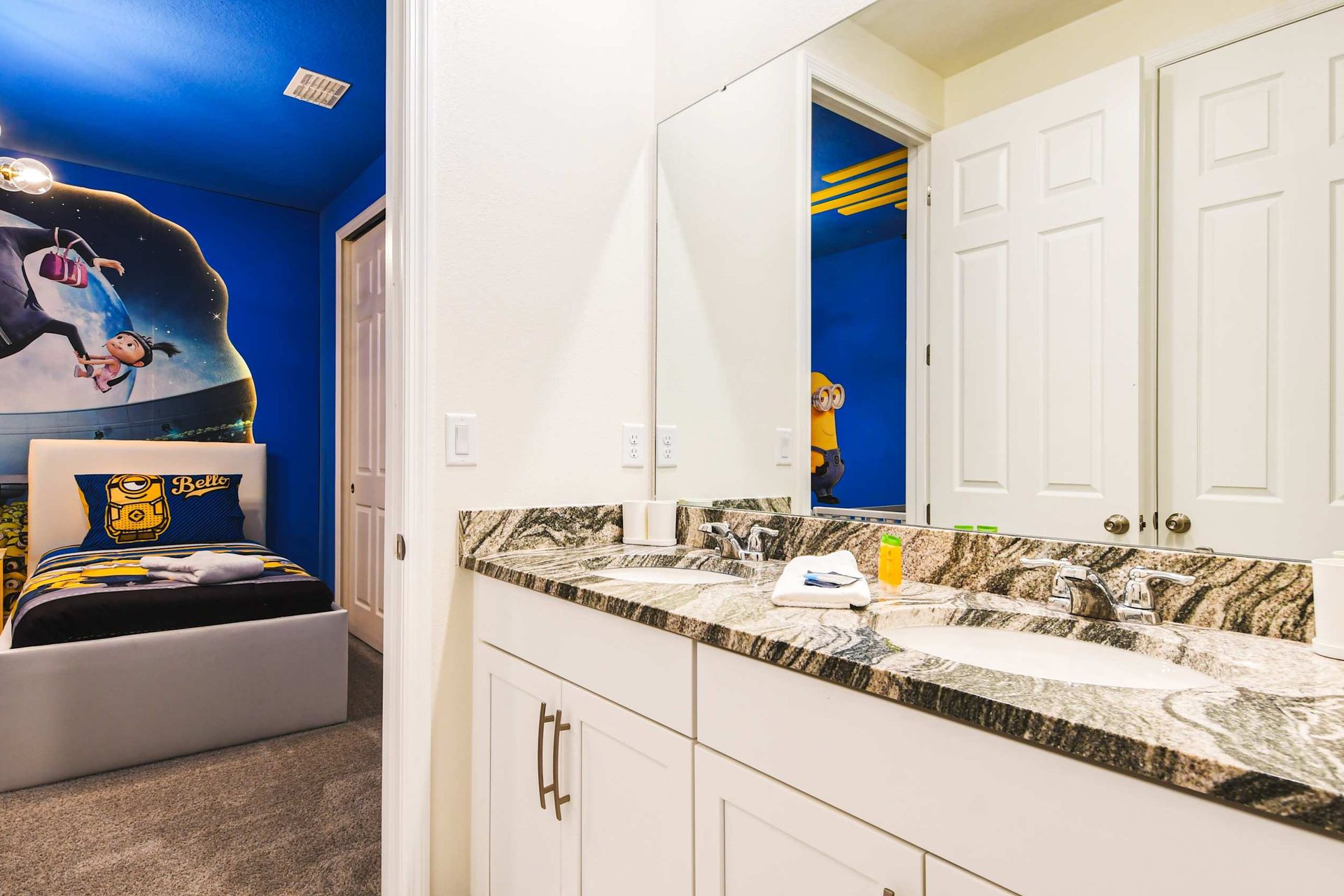 Fun-themed kids' room with vibrant decor and an adjoining double-sink bathroom.