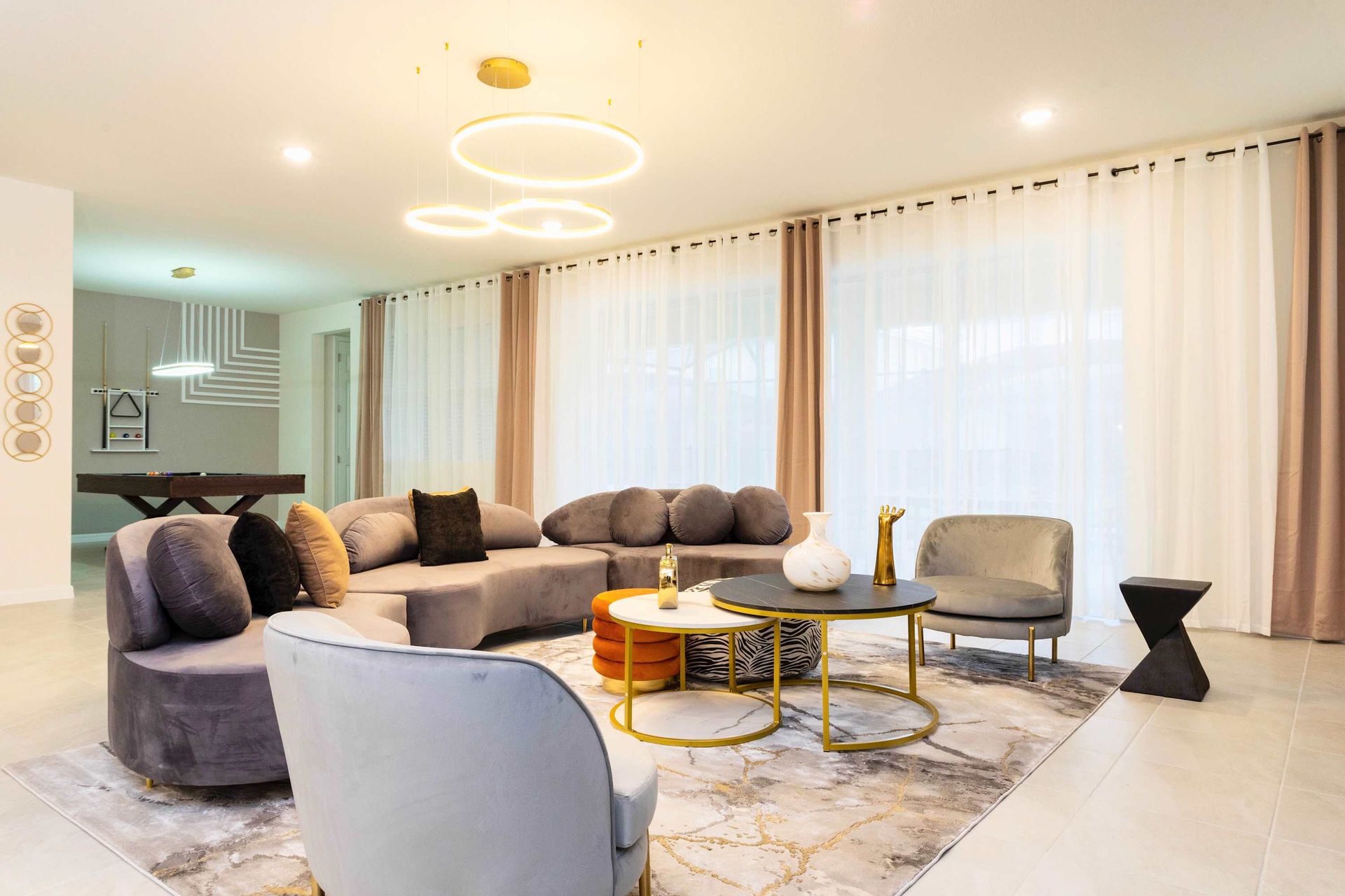 Stylish modern lounge with plush seating, chic decor, and a pool table.