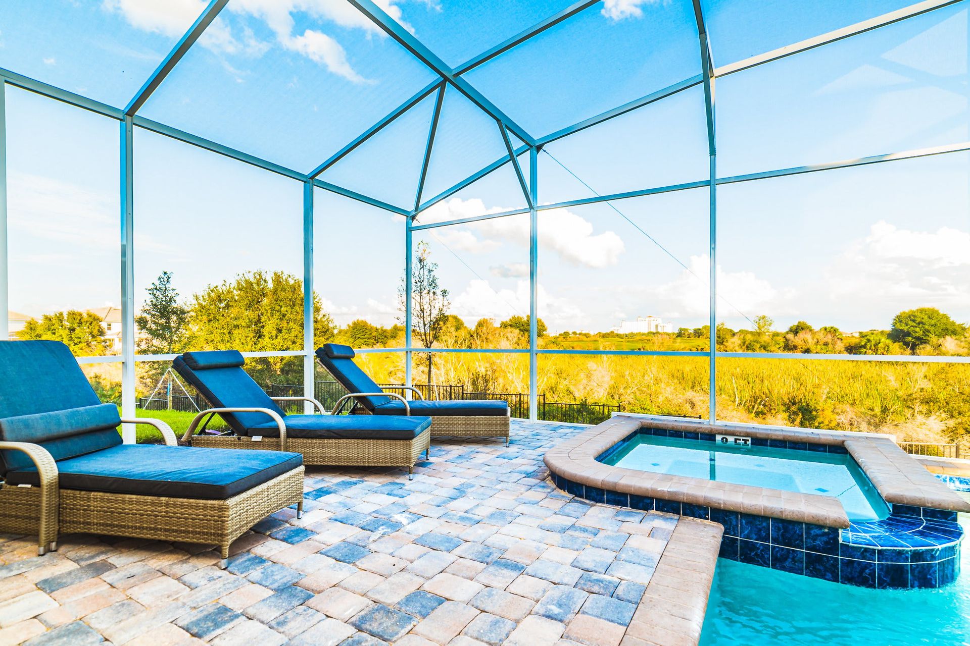 Screened-in pool area with a spa, lounge chairs, and beautiful natural views.