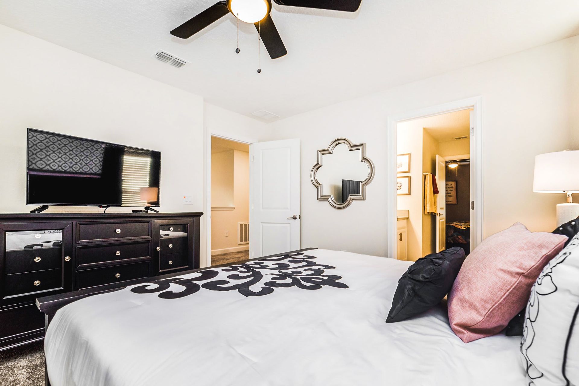 Cozy bedroom with a stylish dresser, wall-mounted TV, and an ensuite bathroom.