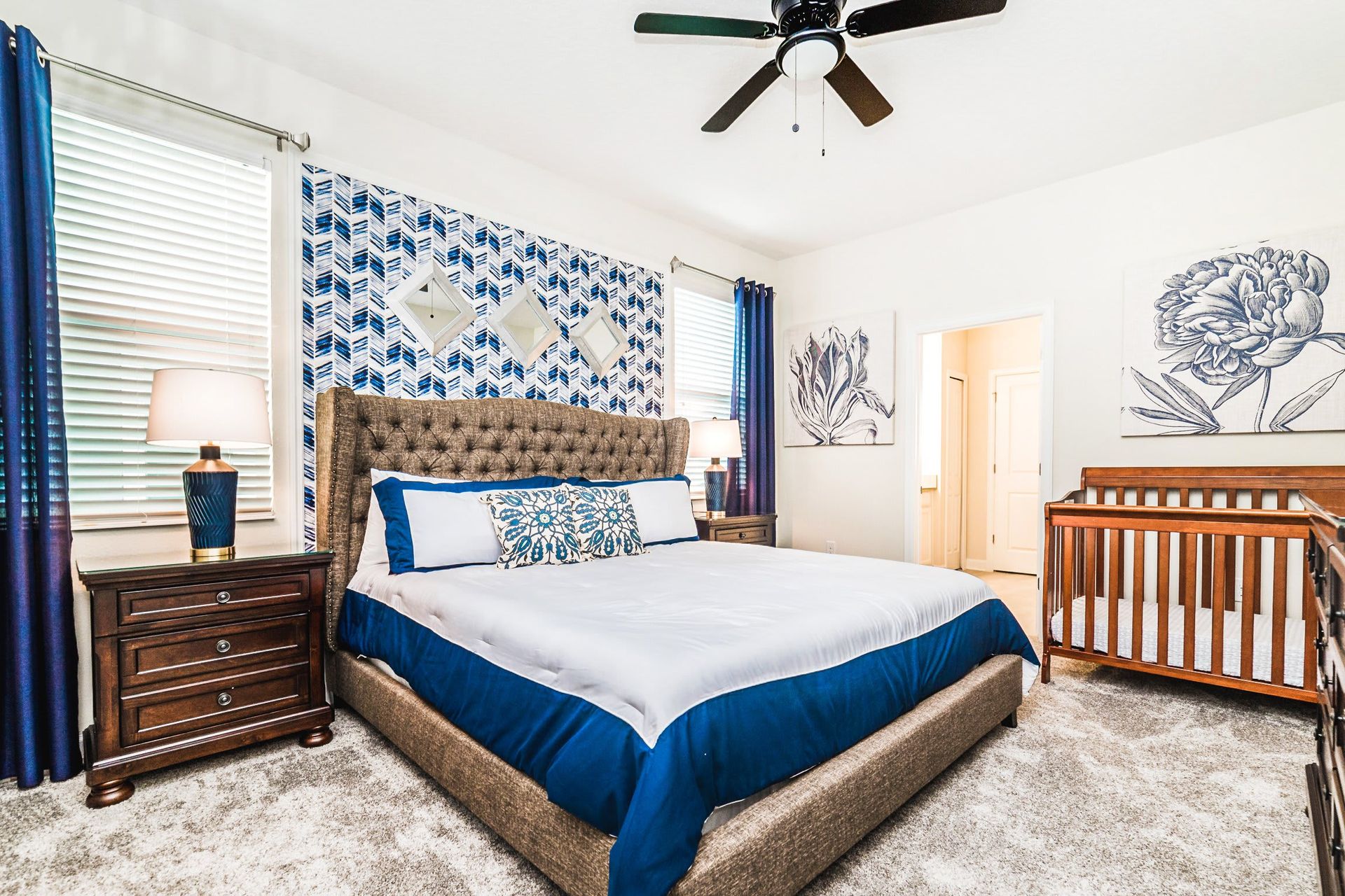 Spacious bedroom with a king bed, cozy crib, stylish decor, and calming blue accents.