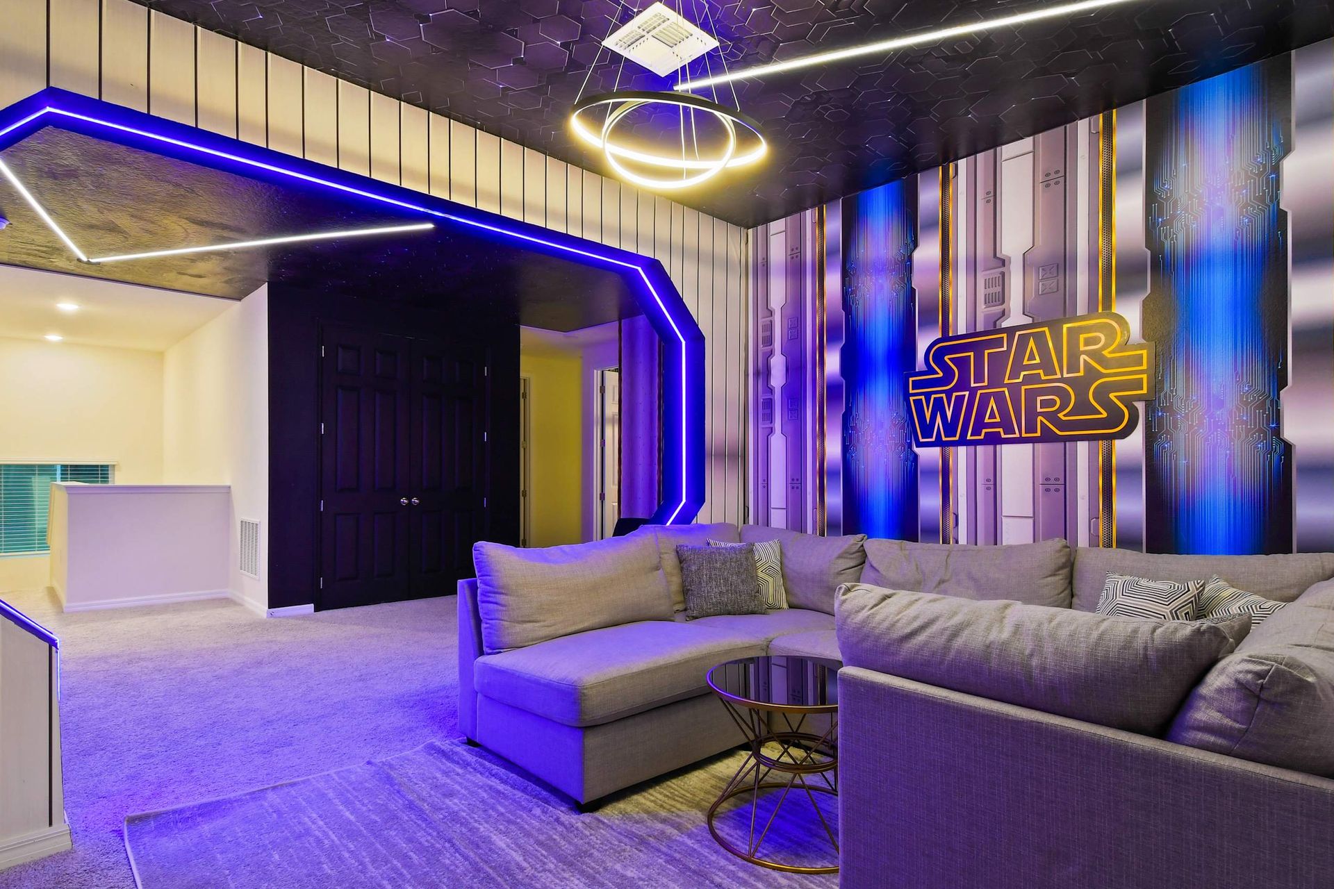 Sci-fi inspired media room with a cozy sectional sofa, neon lighting, and themed decor.