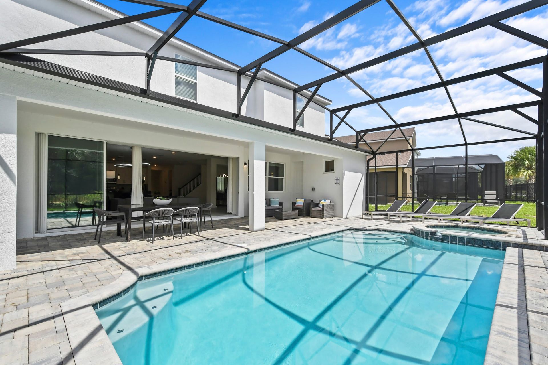 Private screened-in pool and spa with patio seating, perfect for relaxation.