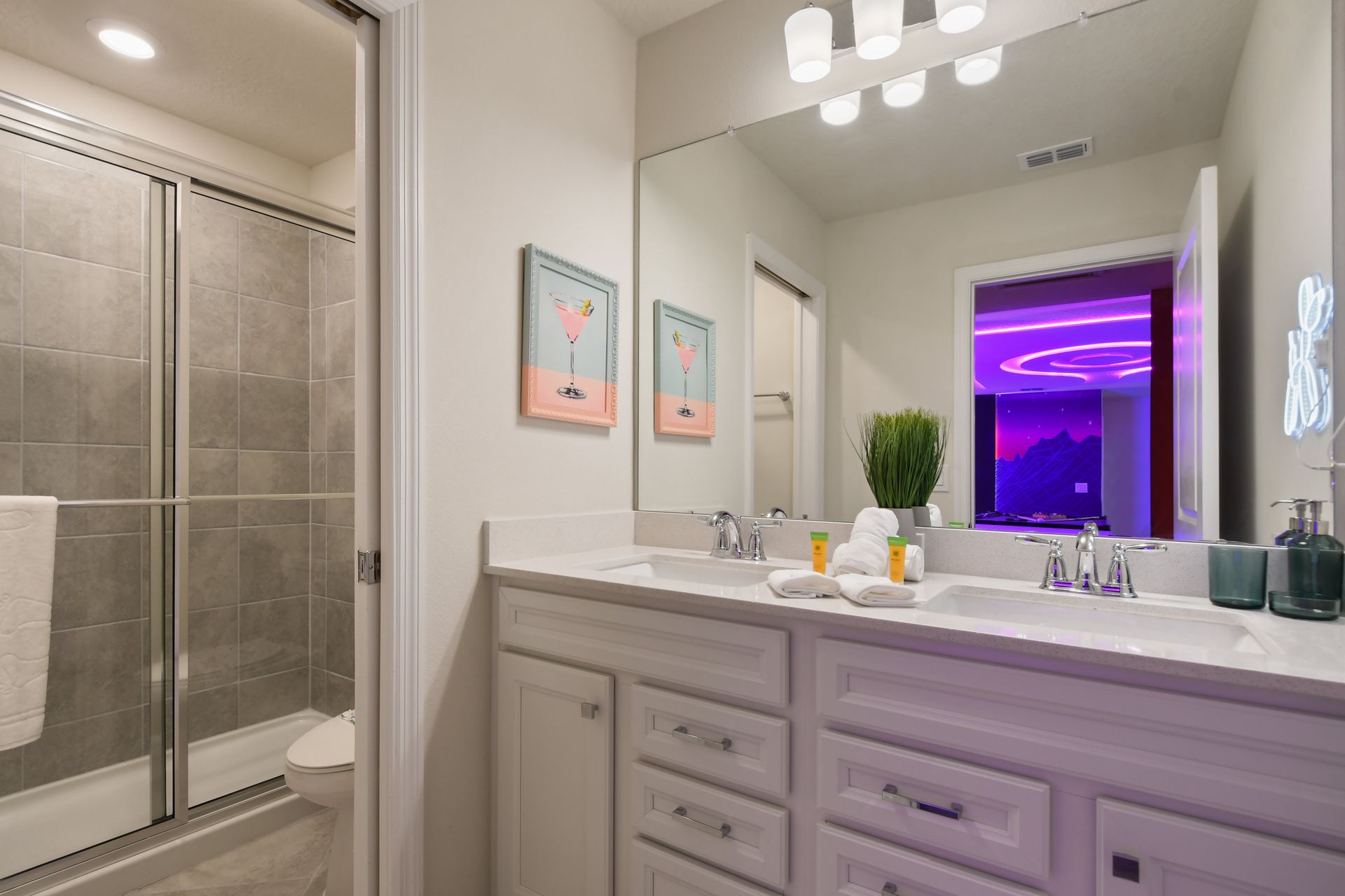 Modern bathroom with dual sinks and a walk-in shower, neon-lit in background.