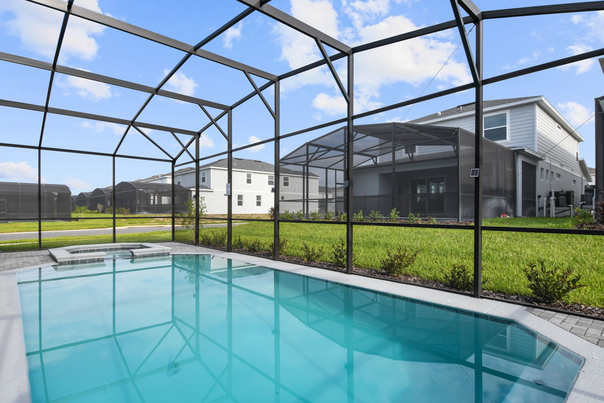 Screened backyard pool with clear water and a view of modern homes.