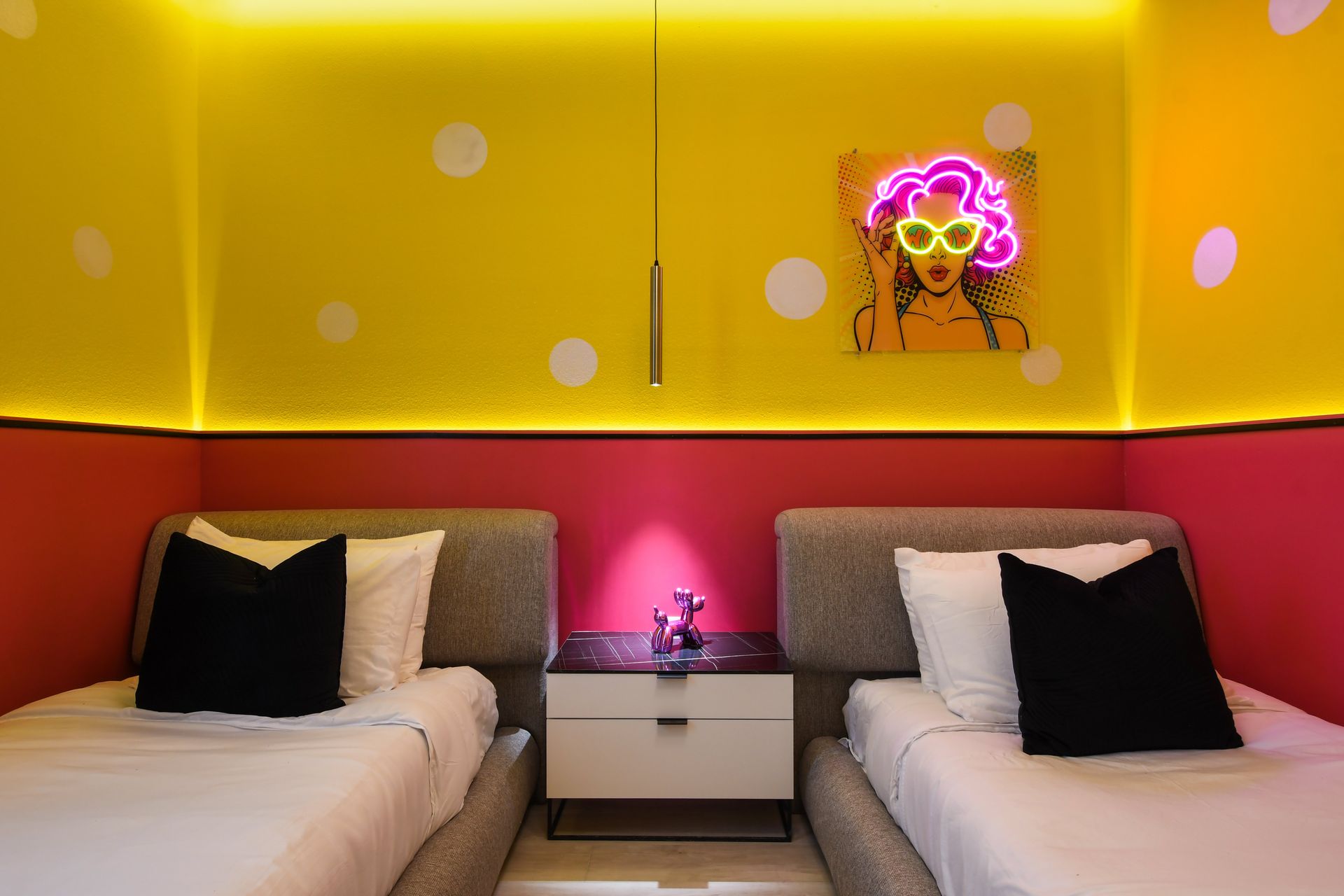 Bright twin bedroom with pop art neon decor, bold colors, and cozy beds.
