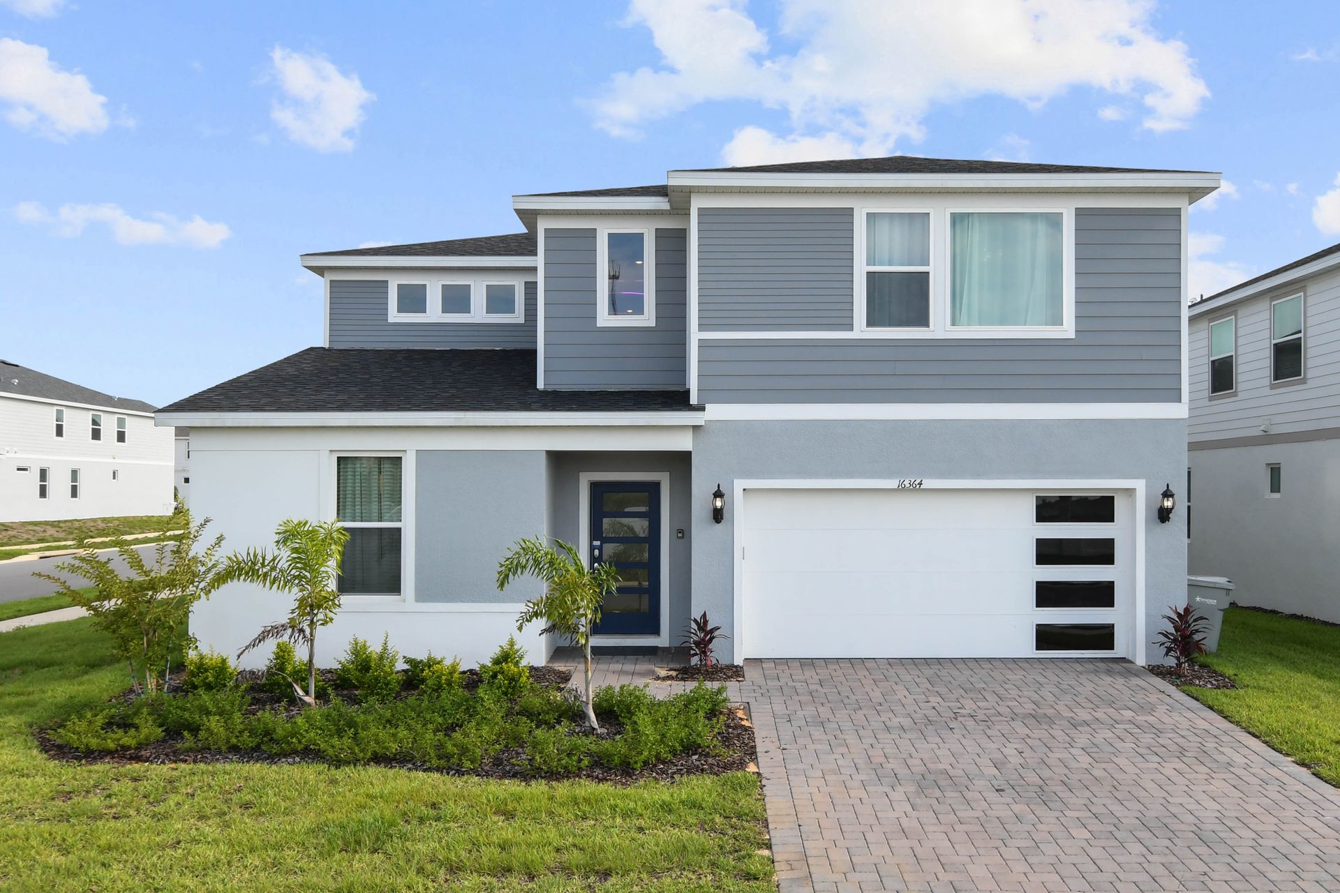 Modern two-story home with a spacious driveway and sleek design.