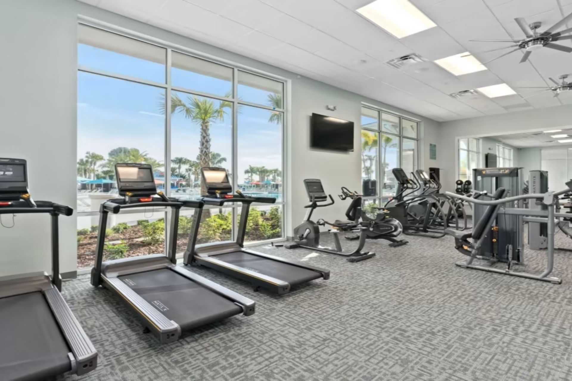 Modern fitness center with top equipment, large windows, and pool views for an energized workout.