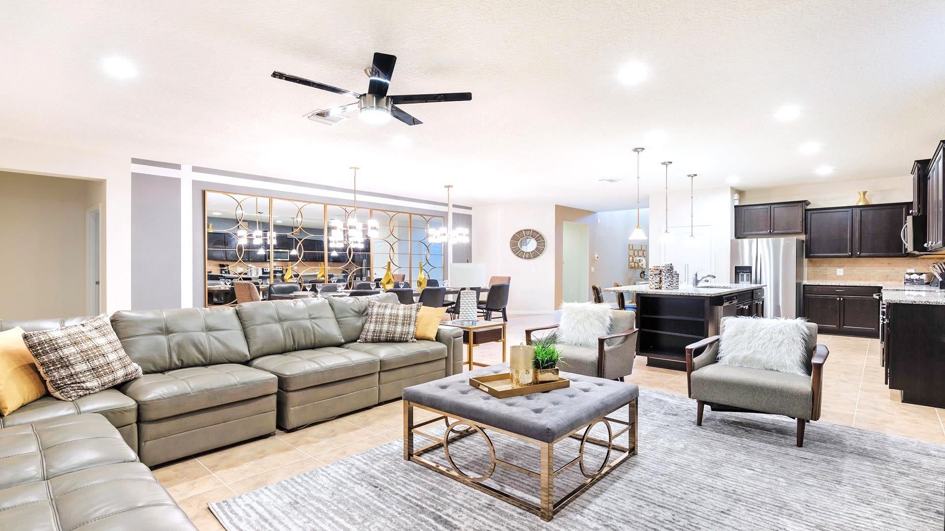 Modern living room with spacious sectional sofa, large TV, chic blue accents, and stylish decor.