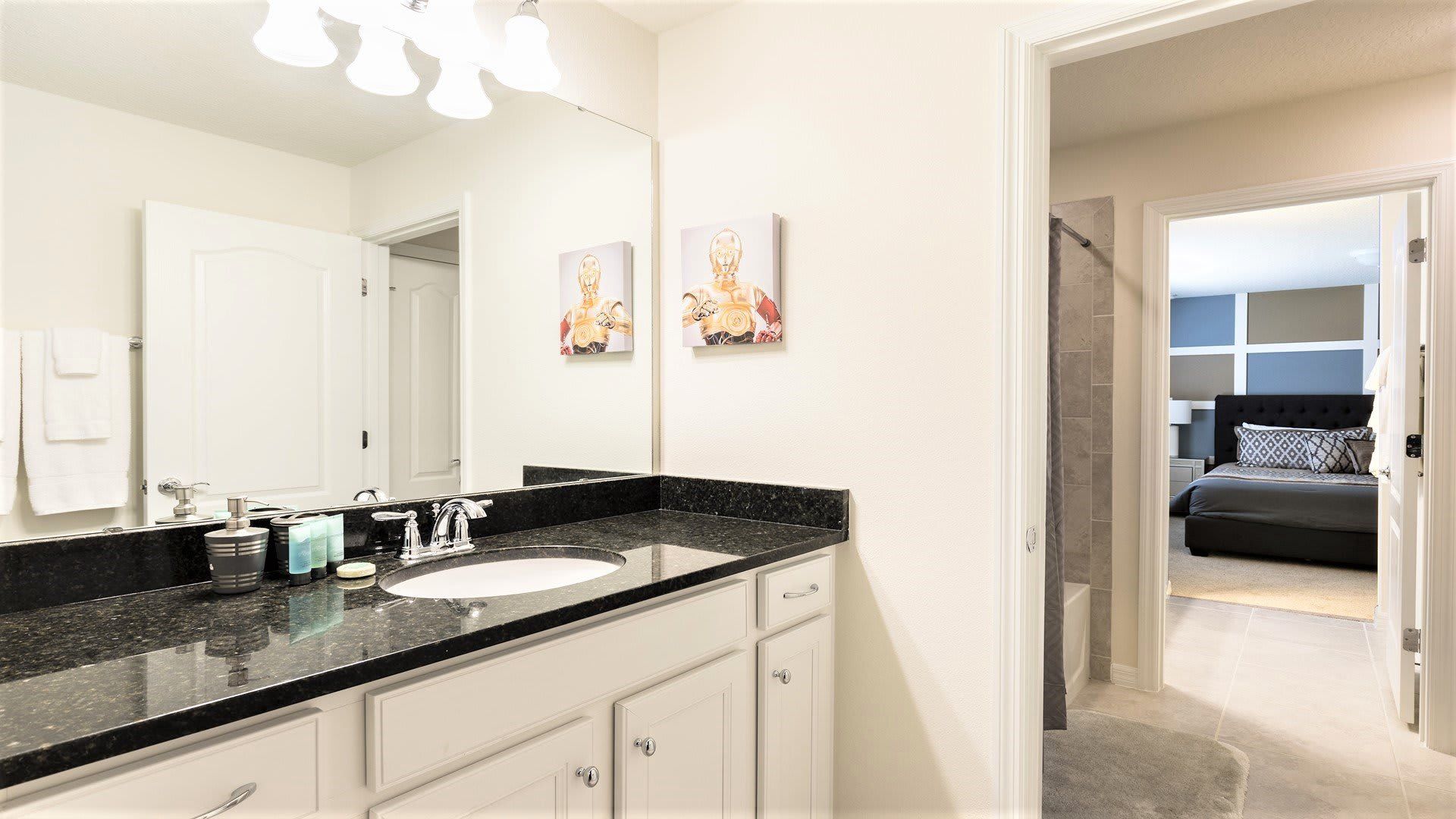 Modern bathroom with dual granite sinks, vibrant decor, and a sleek glass-enclosed shower!