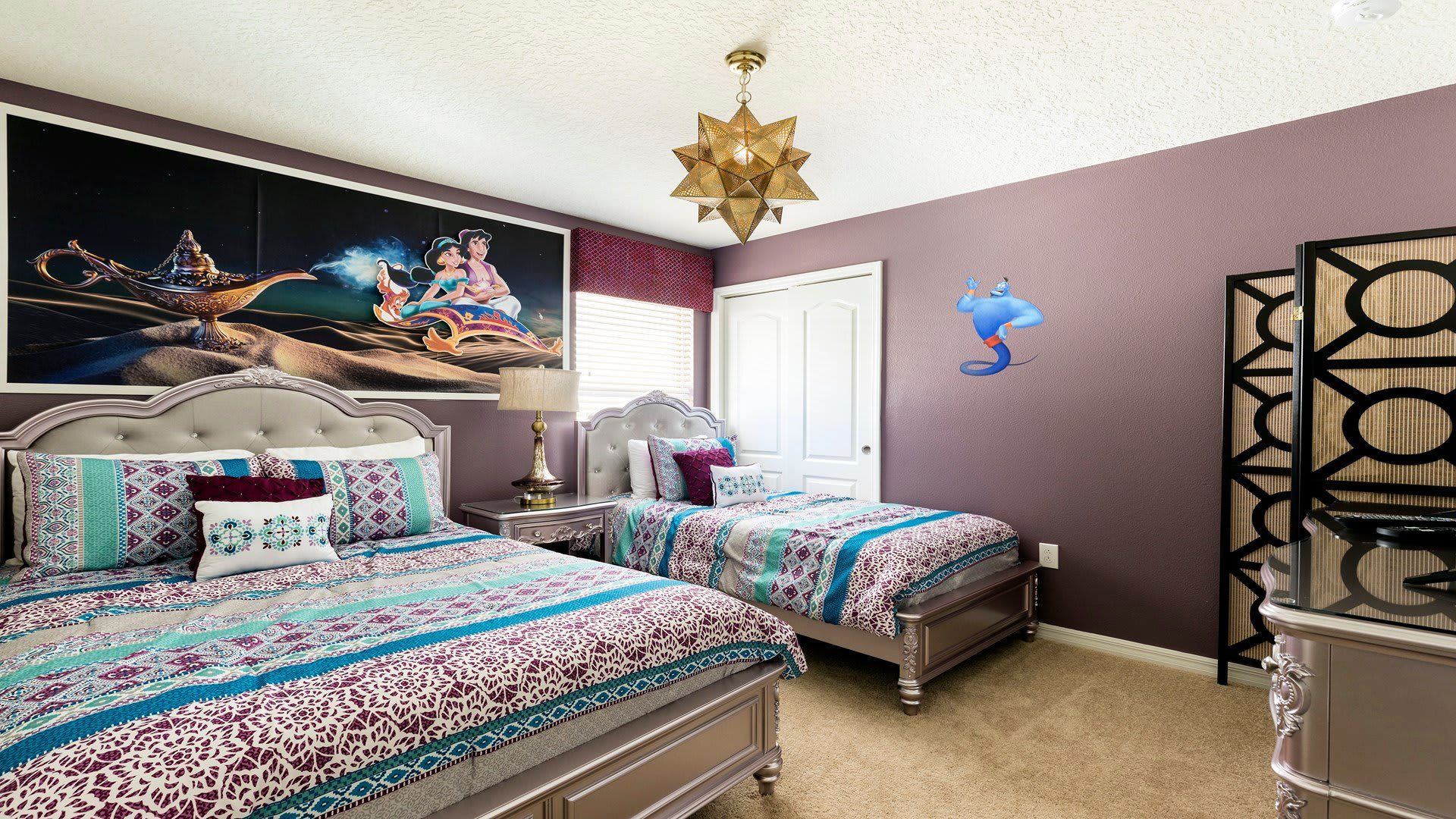 Fairy-tale themed bedroom with vibrant canopy, castle mural, twin beds, and sparkling chandelier.