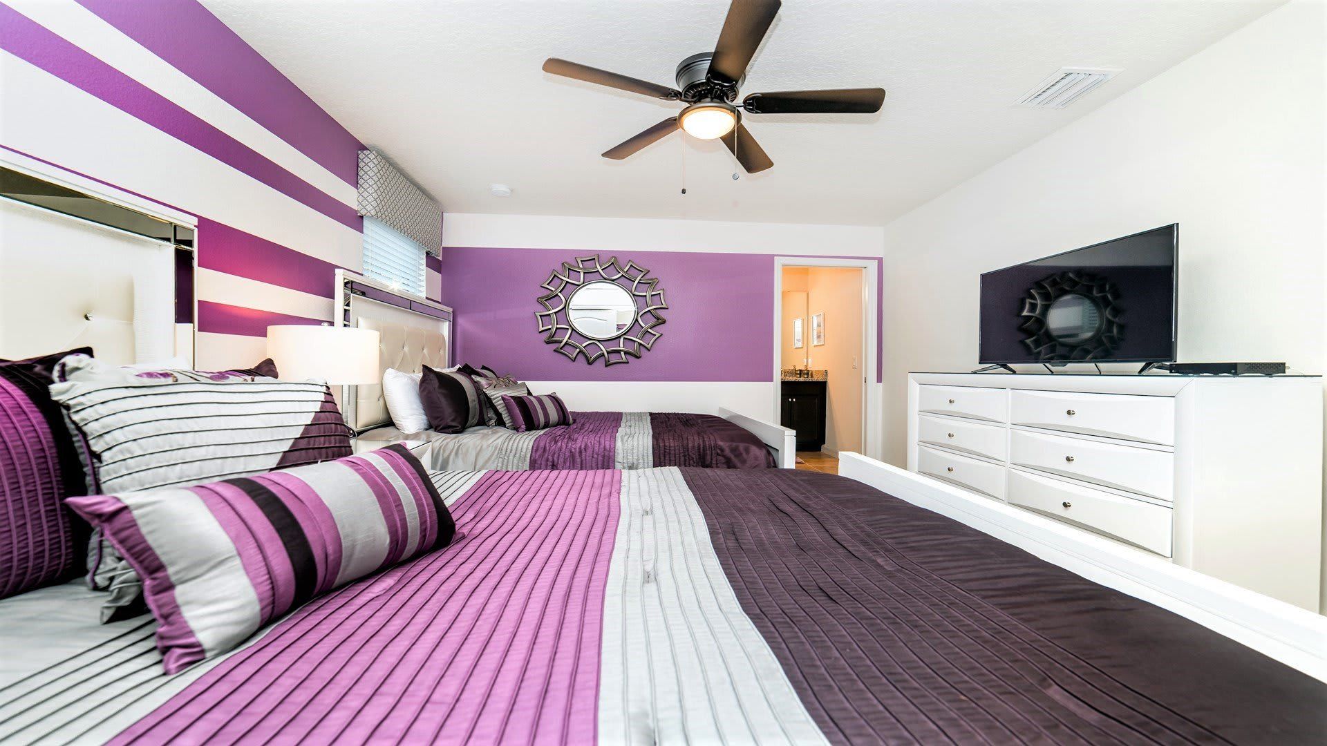 Bright and airy master bedroom with king bed, stylish decor, cozy bench seating, and ceiling fan.