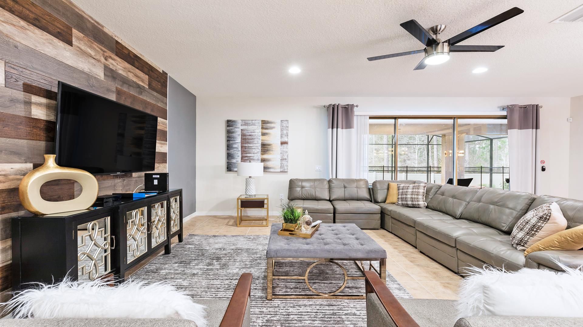 Modern living room with spacious sectional sofa, large TV, chic blue accents, and stylish decor.