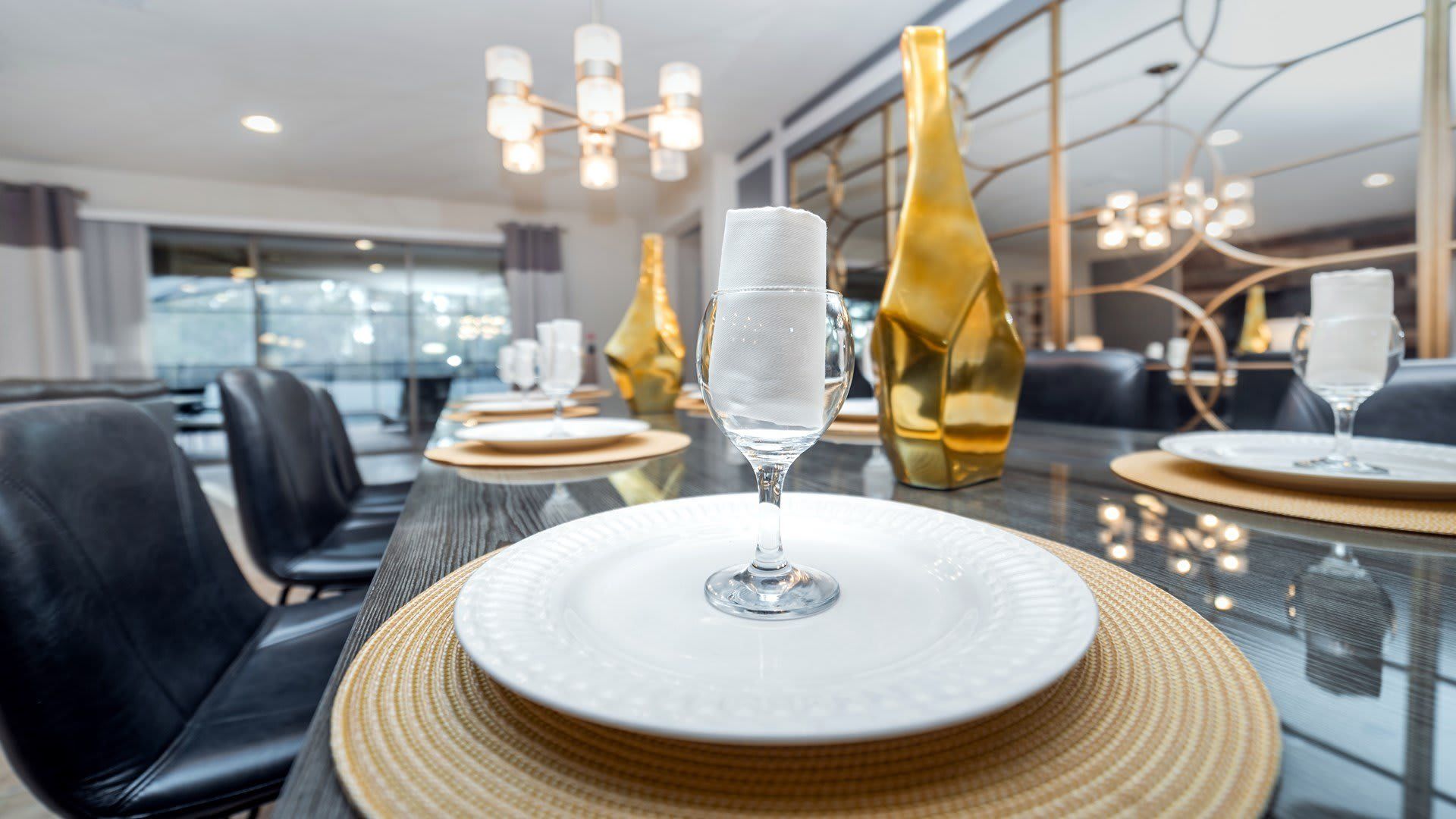 Elegant dining area with seating for 14, modern decor, statement lighting, and stylish mirrors.