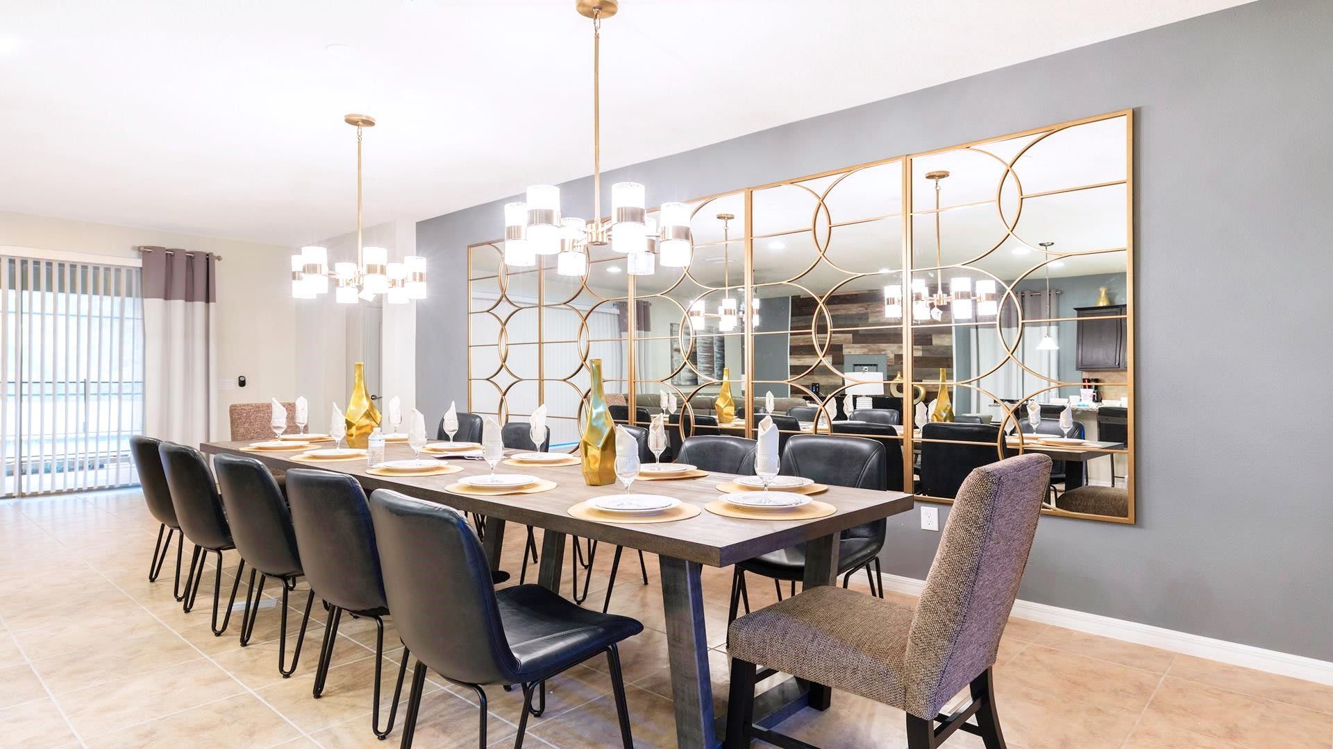 Elegant dining area with seating for 14, modern decor, statement lighting, and stylish mirrors.