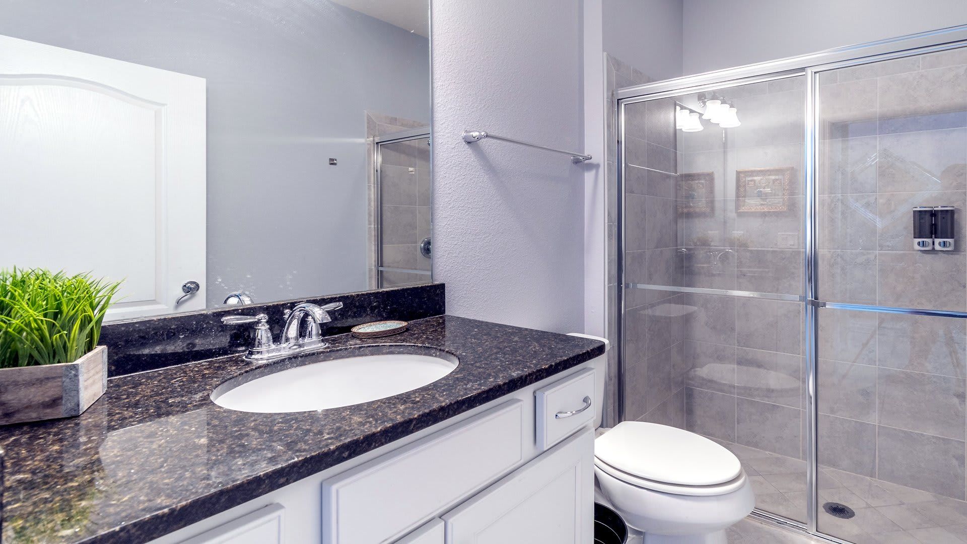 Sleek and modern bathroom with granite countertops and a spacious glass-enclosed shower!