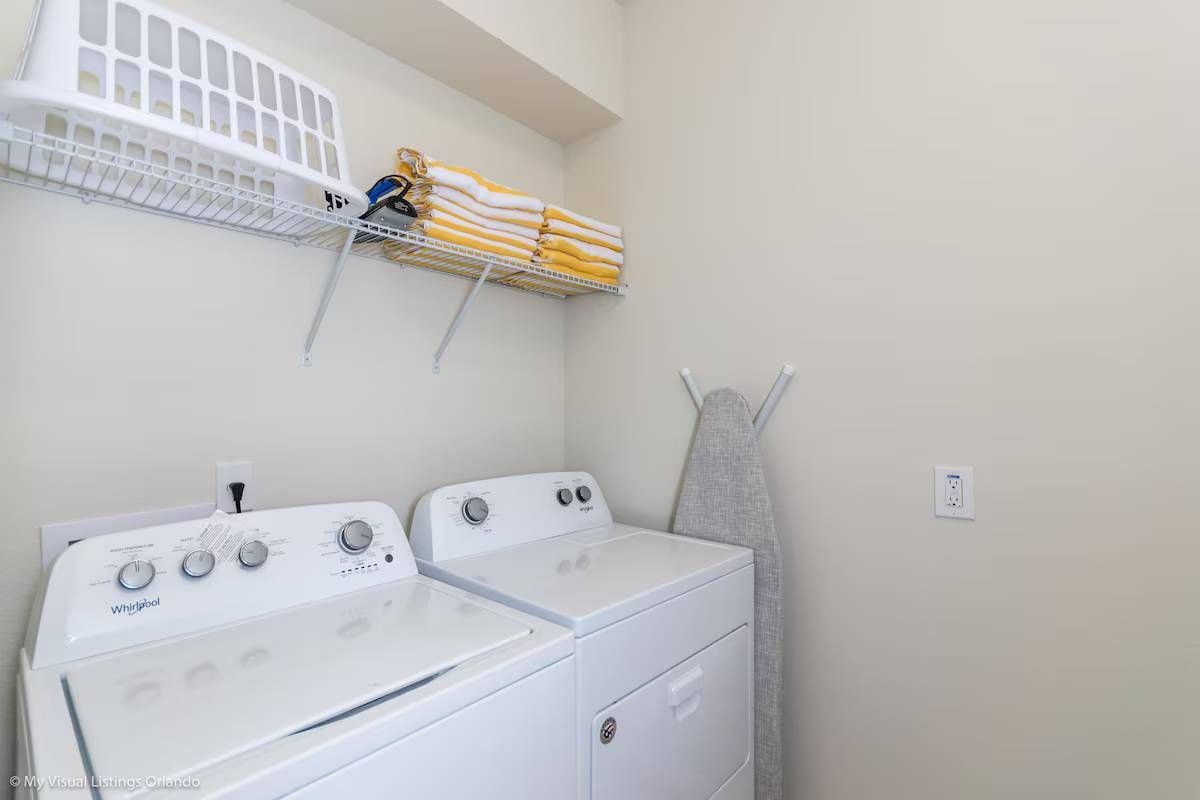 Convenient laundry room with washer, dryer, ironing board & extra storage!