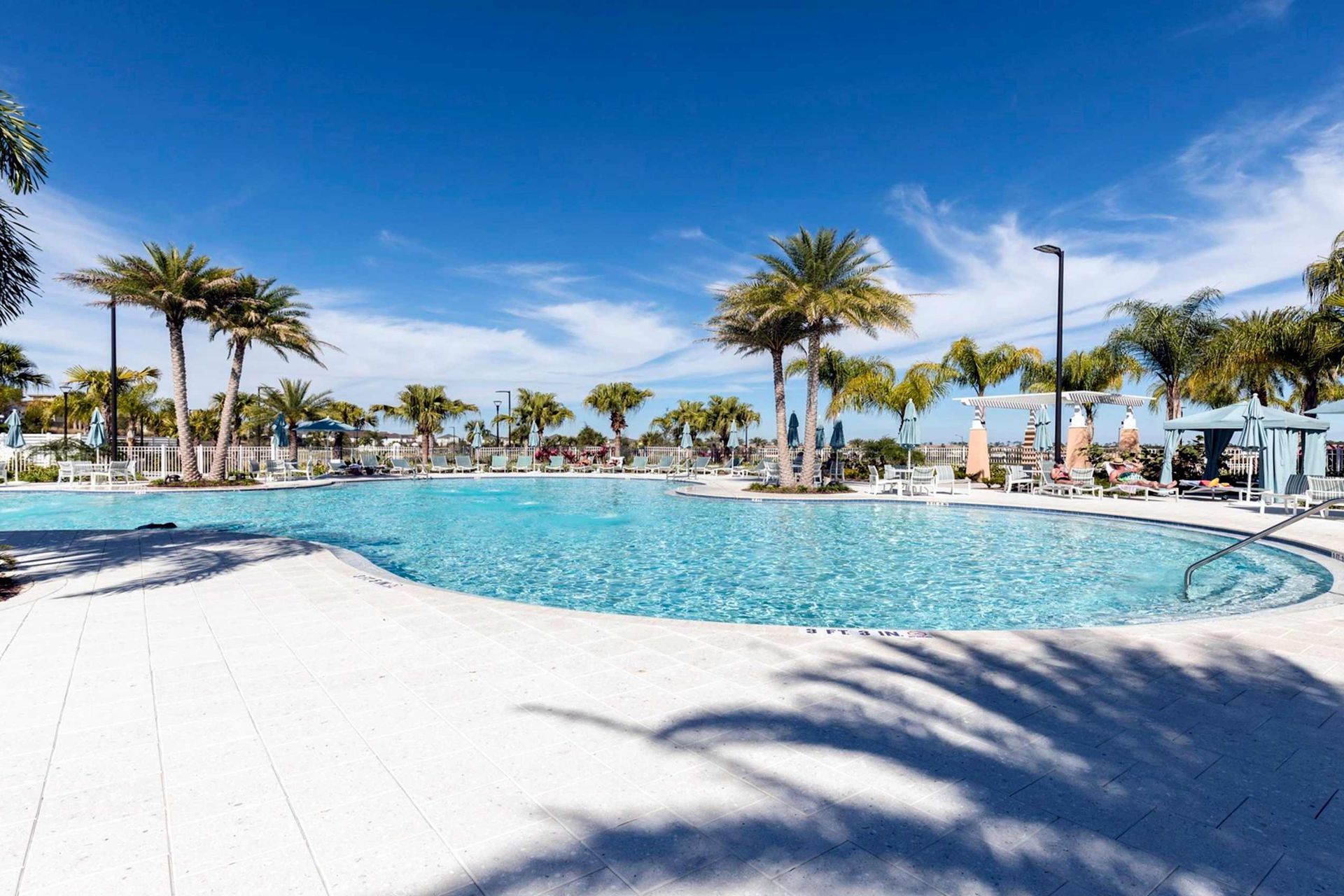 Spacious resort pool with palm trees, shaded loungers, and sunny tropical vibes.
