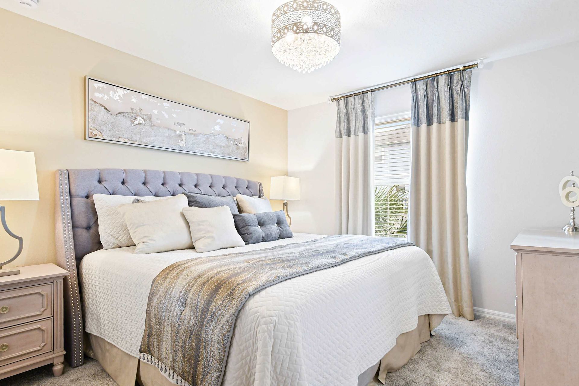 Charming bedroom with soft neutrals, a tufted headboard, and a stunning chandelier!