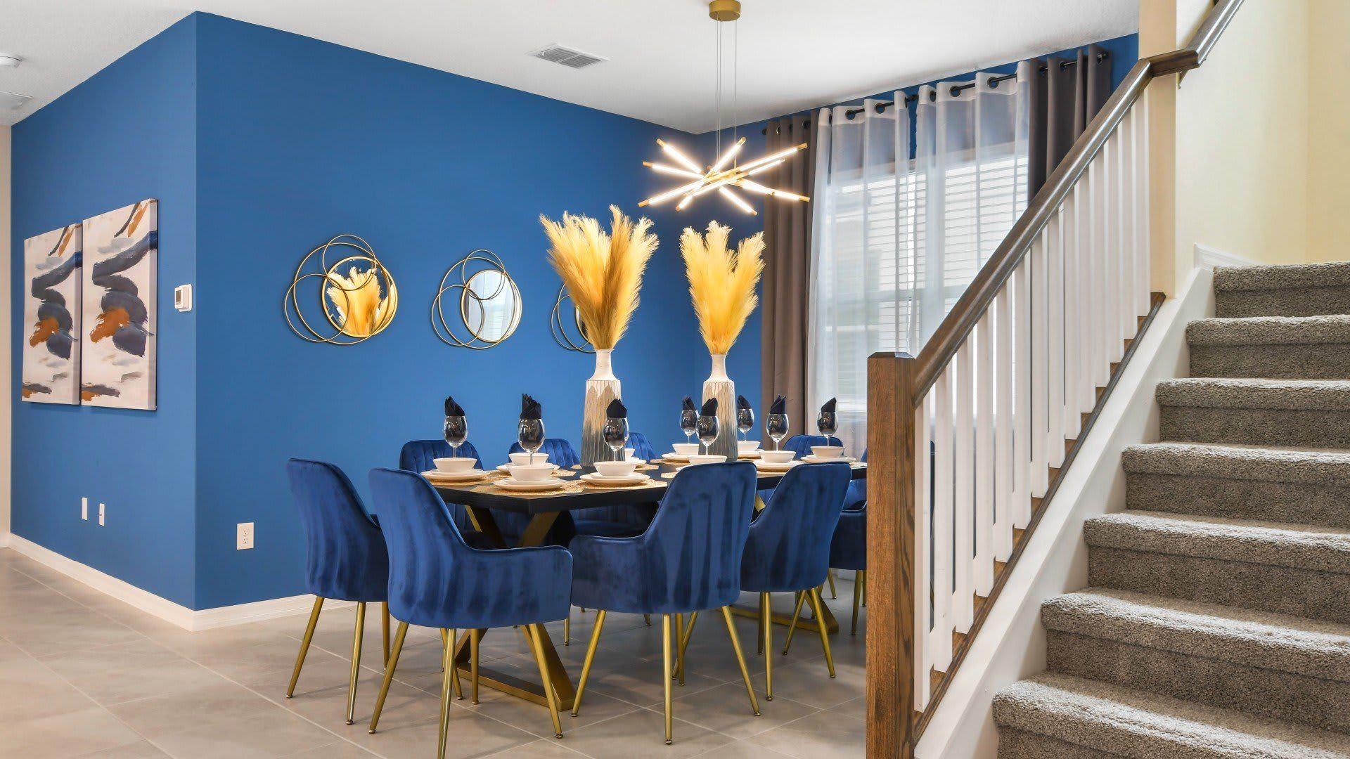 Elegant dining space with bold blue decor, gold accents, and modern lighting!