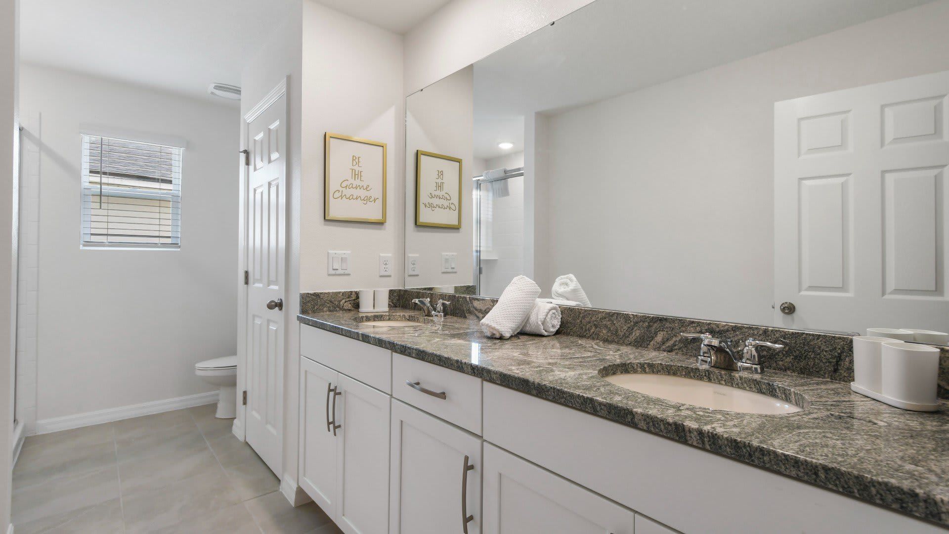 Stylish ensuite bathroom with dual sinks, granite countertops, and a glass shower! 