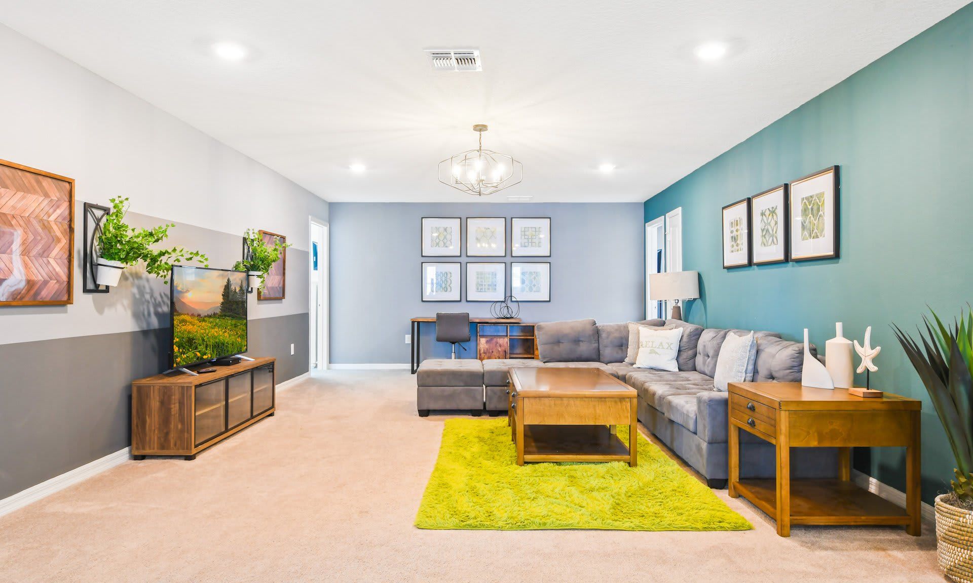 Bright and spacious family room with cozy sectional, large TV, stylish decor, and a dedicated workspace.
